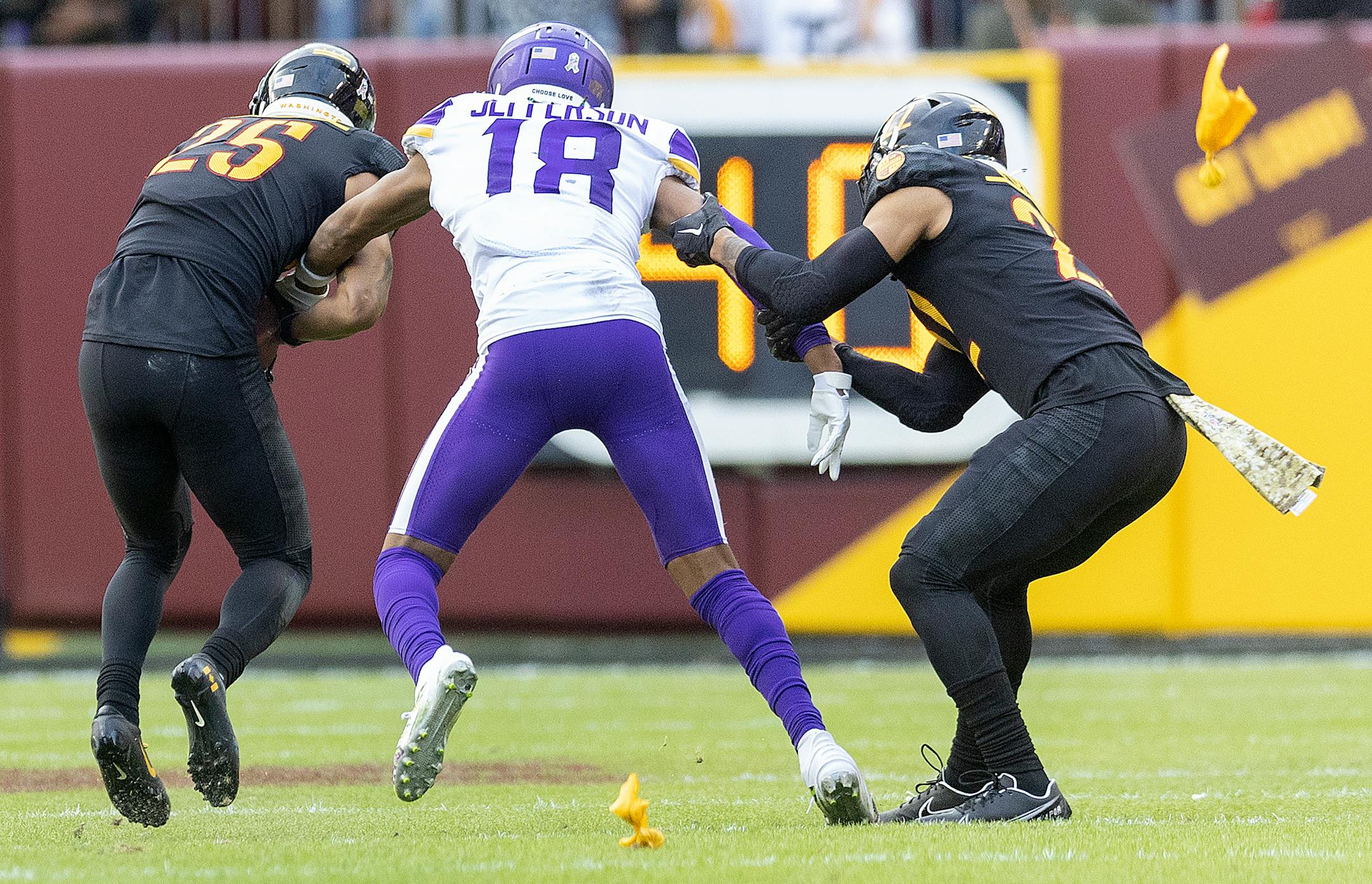 Penalty flags rain down as Minnesota Vikings wide receiver Justin Jefferson (18) is being held by Washington Commanders cornerback Benjamin St-Juste (25), left, and Washington Commanders safety Darrick Forrest (22) in the fourth quarter.