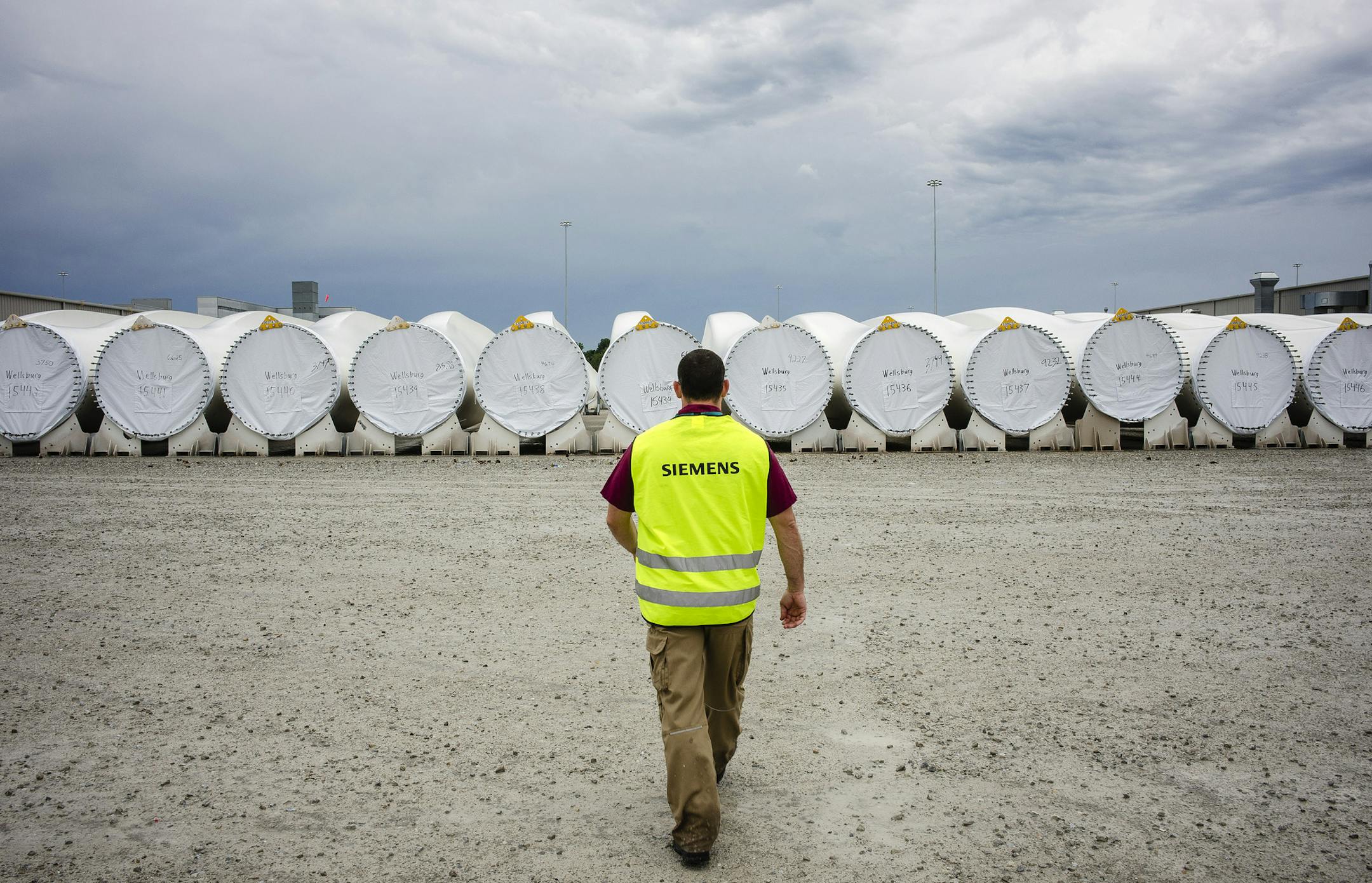 Bloomberg Photo Service 'Best of the Week': A worker walks towards finished turbine blades awaiting transport at the Siemens AG turbine blade plant in Fort Madison, Iowa, U.S., on Wednesday, Aug. 20, 2014. The U.S. Export-Import Bank agreed to lend $65 million for Peruvian wind farms that will use Siemens AG turbines made in Fort Madison and at another Siemens plant in Kansas. Photographer: Timothy Fadek/Bloomberg ORG XMIT: 509474689