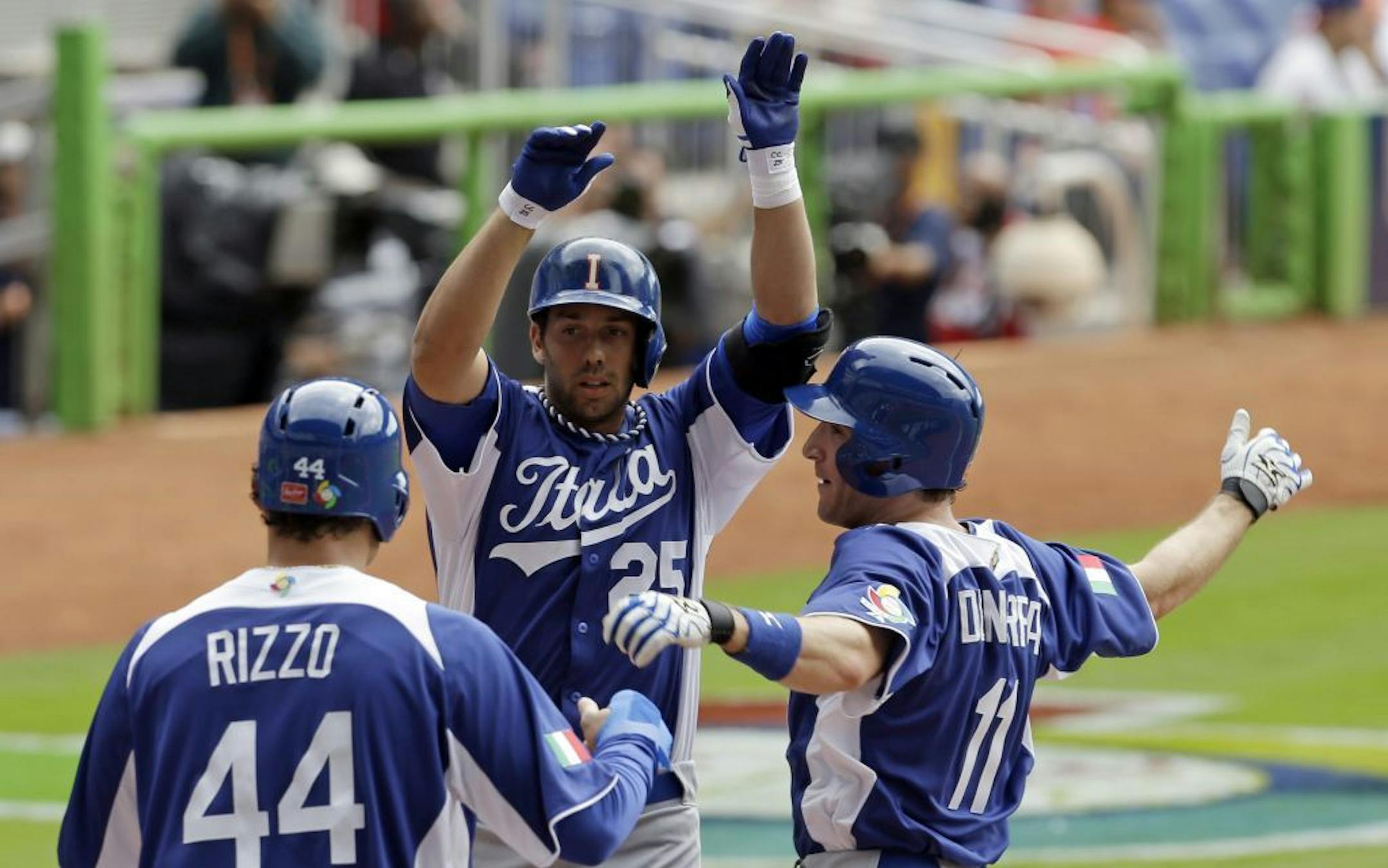Italy's Chris Colabello (25) is congratulated at home plate by teammates Anthony Rizzo (44) and Chris Denorfia (11) after Colabello hit a three-run home run against the Dominican Republic in the World Baseball Classic.