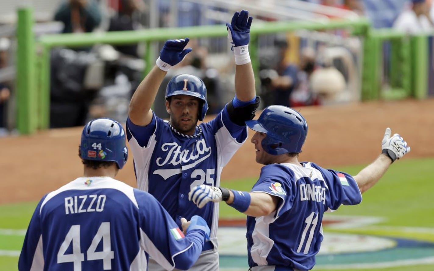 Italy's Chris Colabello (25) is congratulated at home plate by teammates Anthony Rizzo (44) and Chris Denorfia (11) after Colabello hit a three-run home run against the Dominican Republic in the World Baseball Classic.