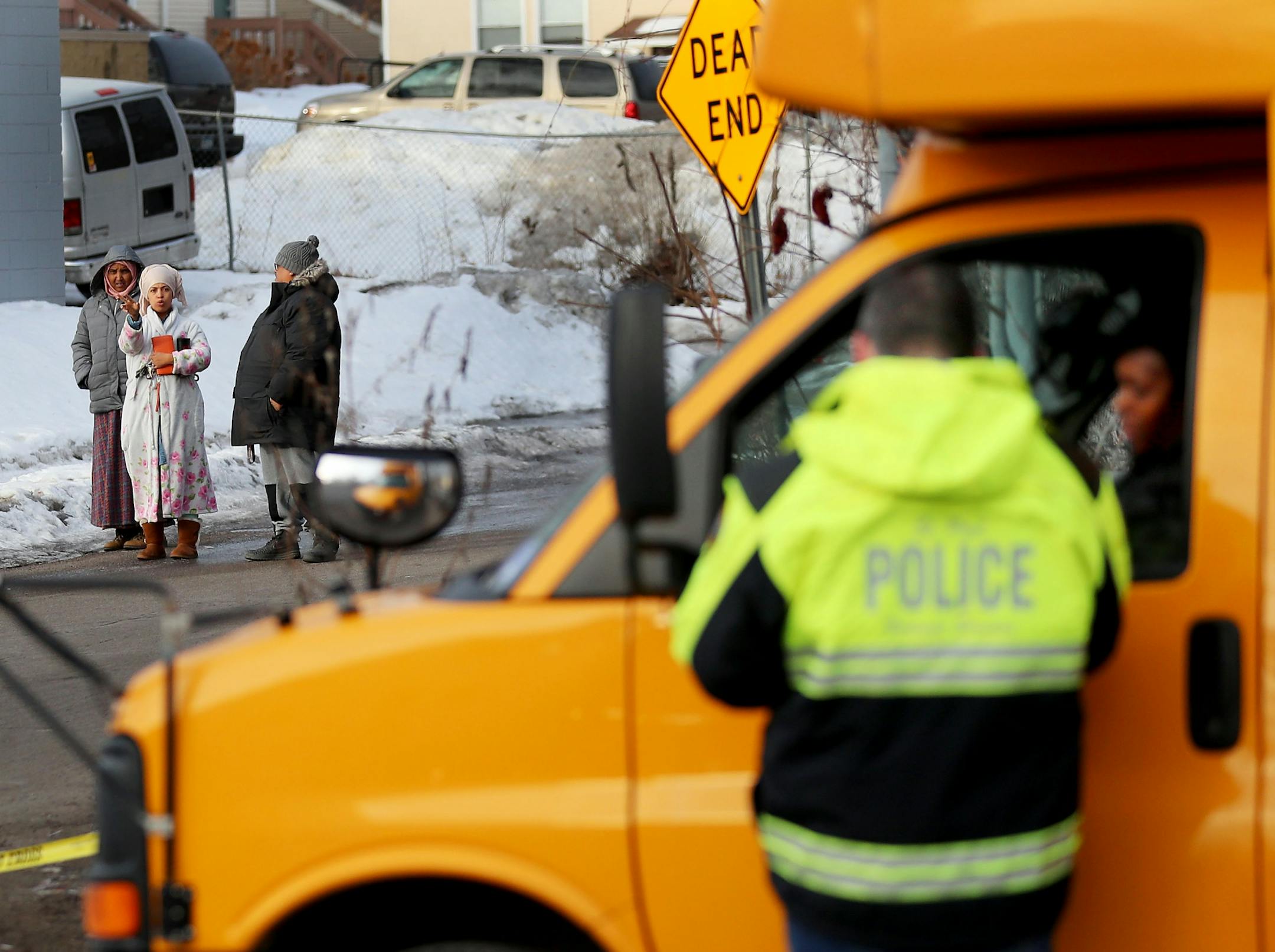 Bystanders look on as a police officer talks to a school bus driver at the scene along Robert St. Thursday morning on St. Paul's west side.