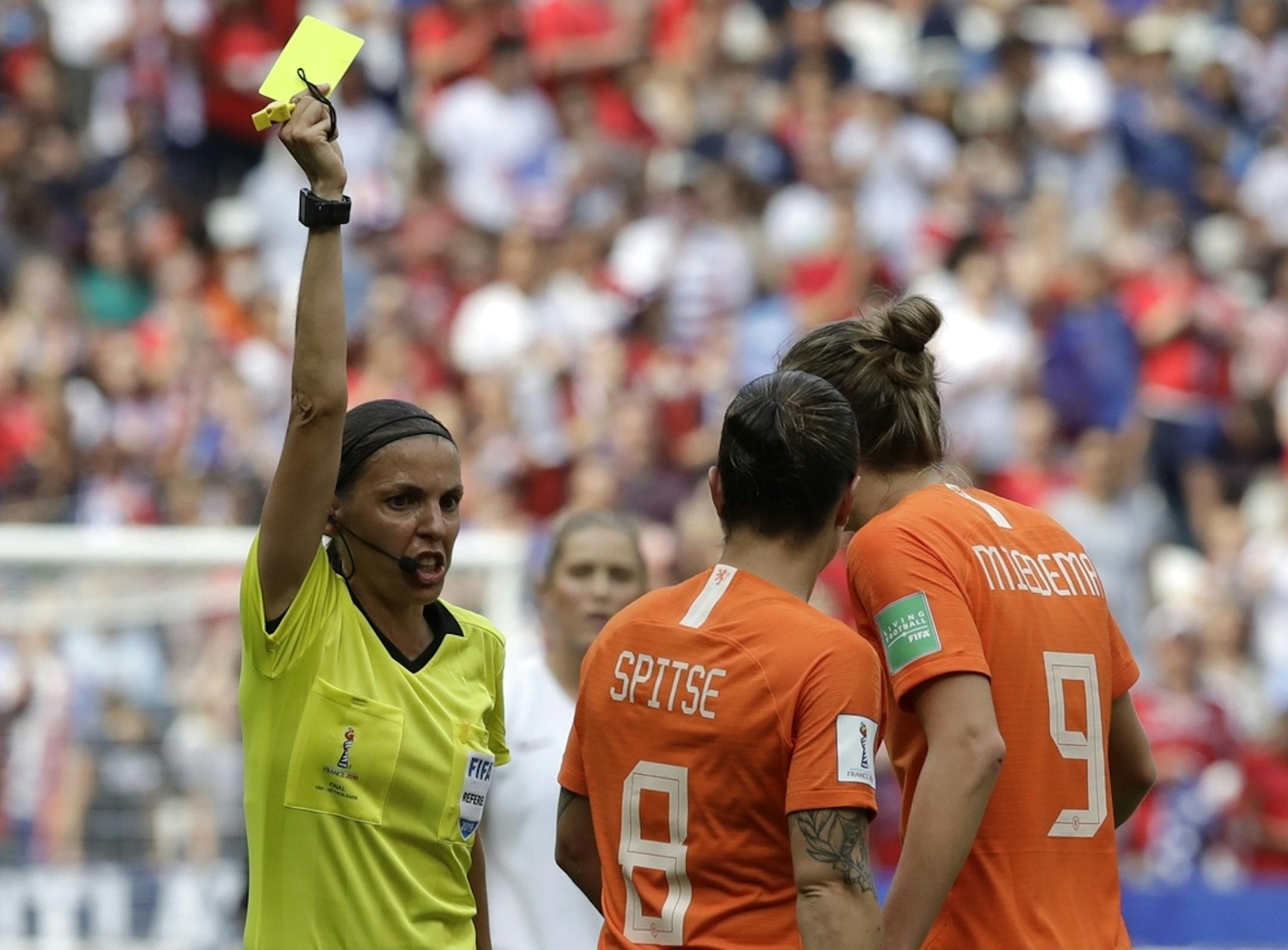 Netherlands' Vivianne Miedema, right, talks to French referee Stephanie Frappart, left, as she shows a yellow card to Netherlands' Sherida Spitse, center, during the Women's World Cup final soccer match between US and The Netherlands at the Stade de Lyon in Decines, outside Lyon, France, Sunday, July 7, 2019.