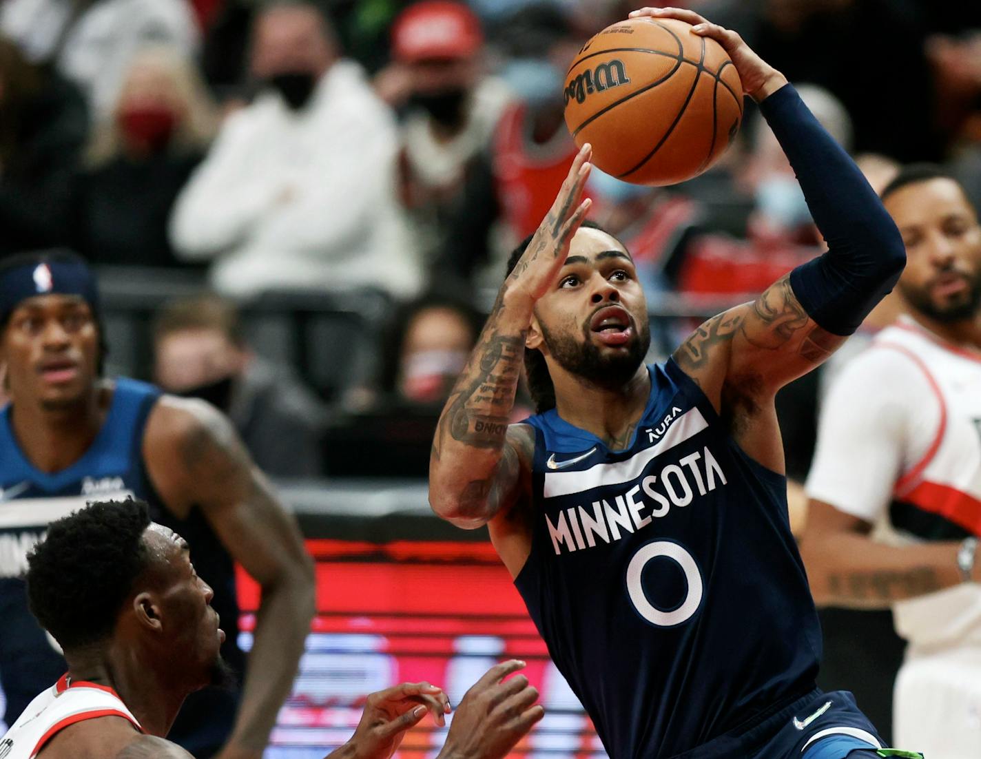 Minnesota Timberwolves guard D'Angelo Russell, right, drives to the basket past Portland Trail Blazers forward Nassir Little, left, during the first half of an NBA basketball game in Portland, Ore., Sunday, Dec. 12, 2021. (AP Photo/Steve Dipaola)