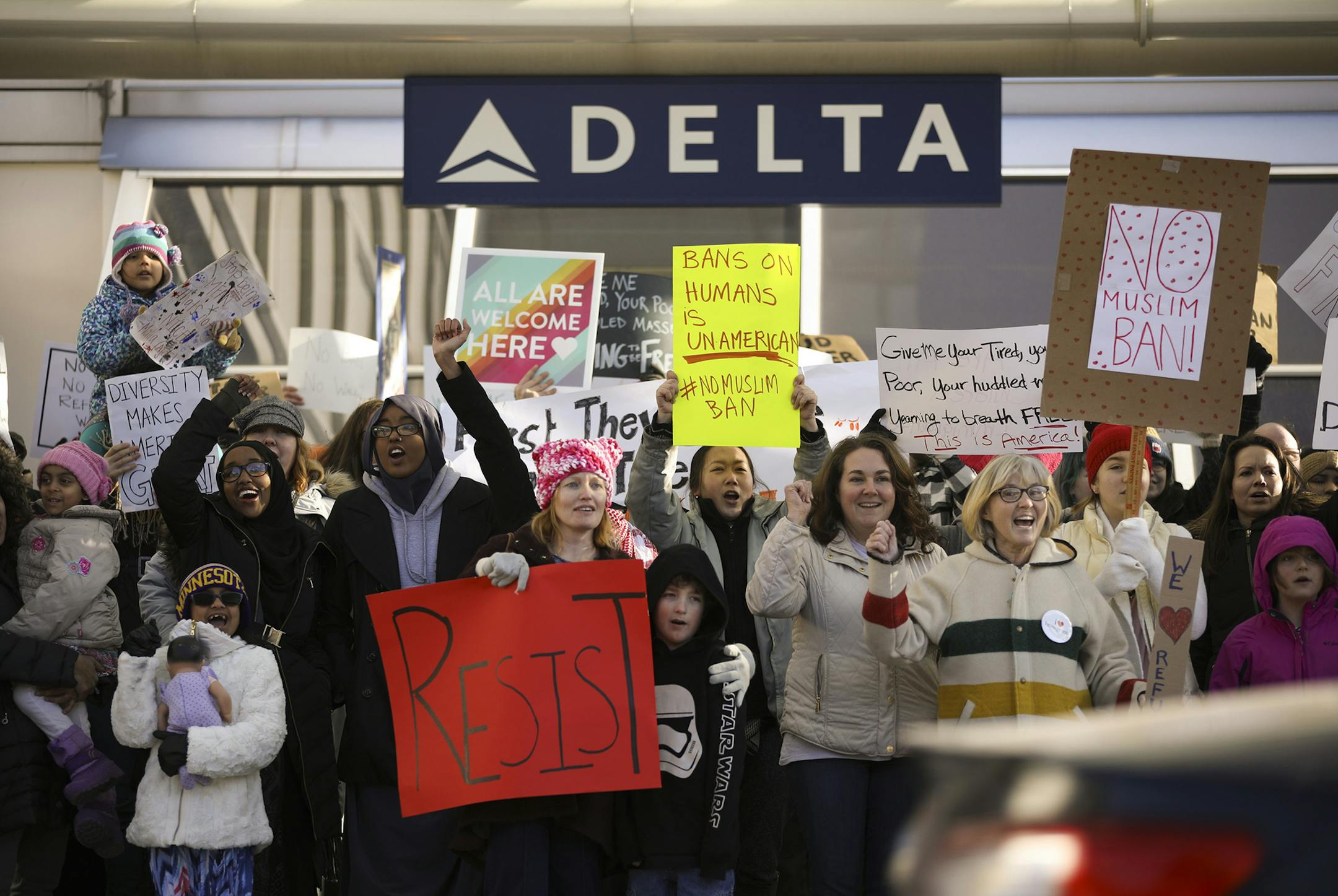 Demonstrators hold signs and chant as they stood across the road from the arrival area at Terminal 1 at Minneapolis&#xf1;Saint Paul International Airport, to protest against President Trump's travel ban on refugees and citizens of seven Muslim-majority nations, in Hennepin County, Minneapolis on Sunday, Jan. 29, 02017. (Jeff Wheeler/Star Tribune via AP) ORG XMIT: MIN2017020710414619