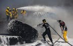 Israeli firefighters extinguish tractor tires in a farmland set on fire by a kite with attached burning cloth launched from Gaza on the Israeli side o