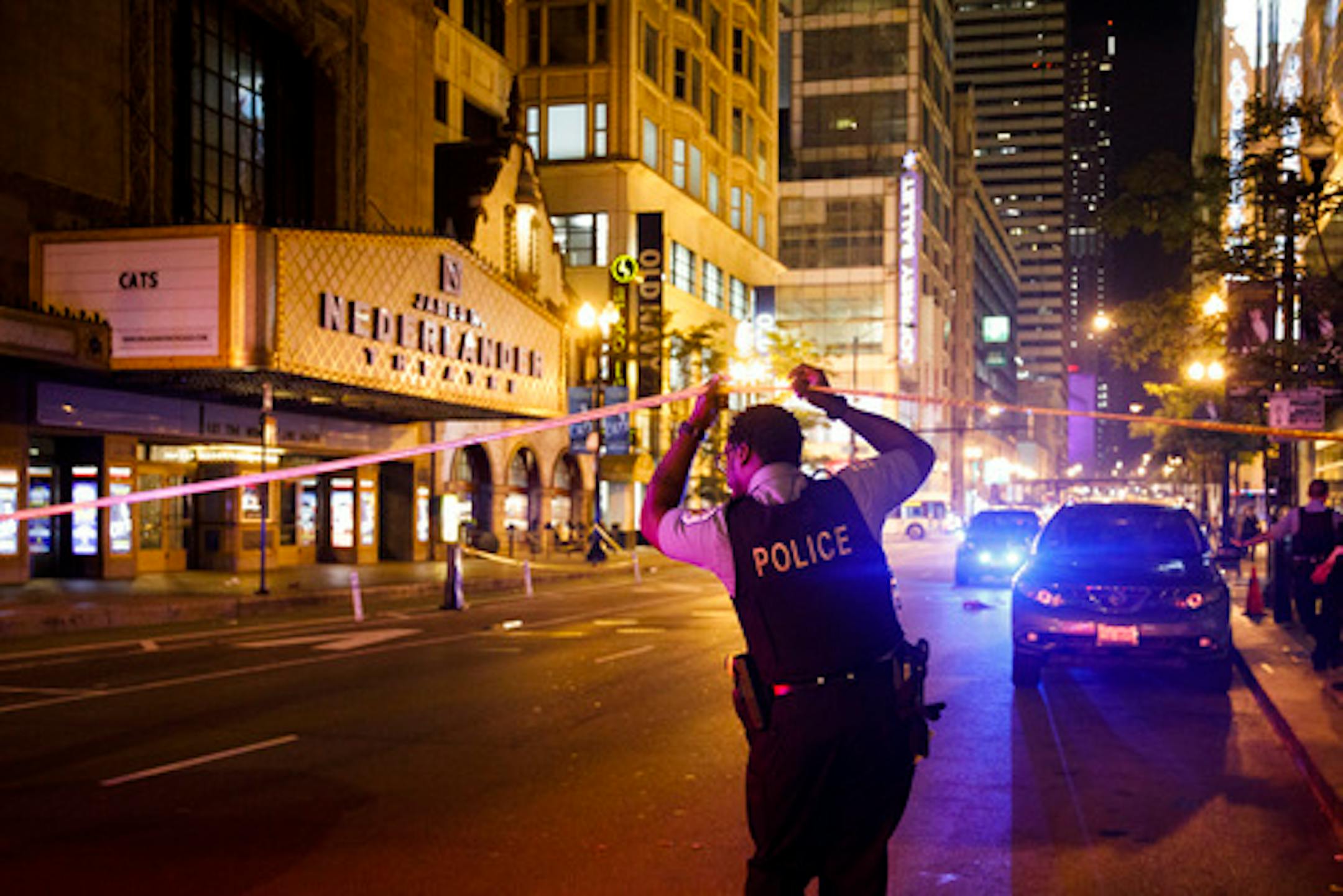 FILE - An officer walks under police tape near the intersection of West Randolph and North State Street near the scene where a woman and man were stabbed in Chicago earlier this month. Over the weekend, two women who worked with other moms to try to stop gun violence in Chicago were gunned down and killed.