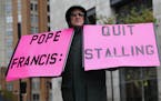 Robert Hoatson, of West Orange, N.J., holds protest signs outside of a hotel hosting the United States Conference of Catholic Bishops' annual fall mee