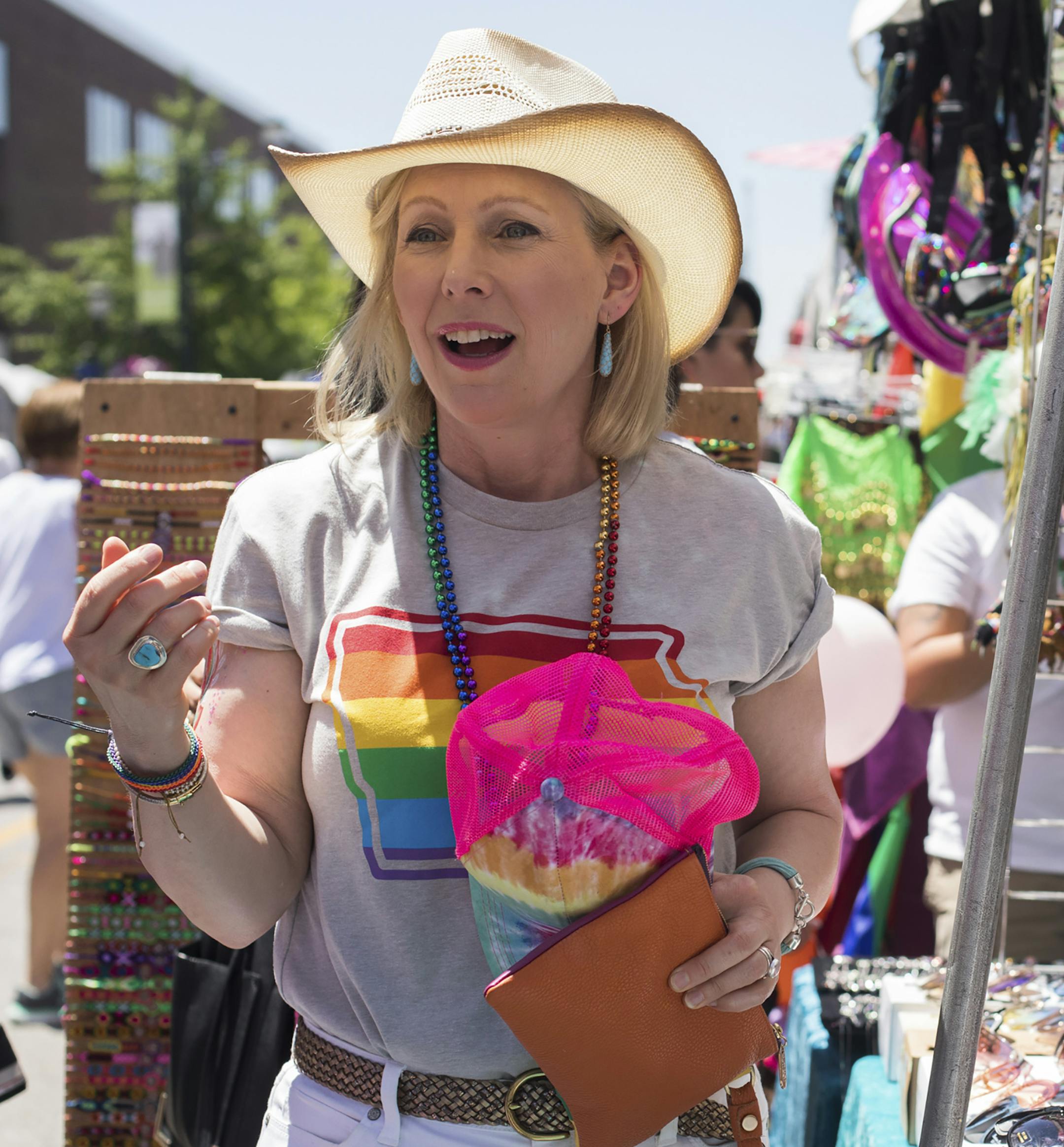 Sen. Kirsten Gillibrand (D-N.Y.), a Democratic candi­date for presi­dent, tries on hats during the Capital City Pride Festival in Des Moines, Iowa, June 8, 2019. (Rachel Mummey/The New York Times)