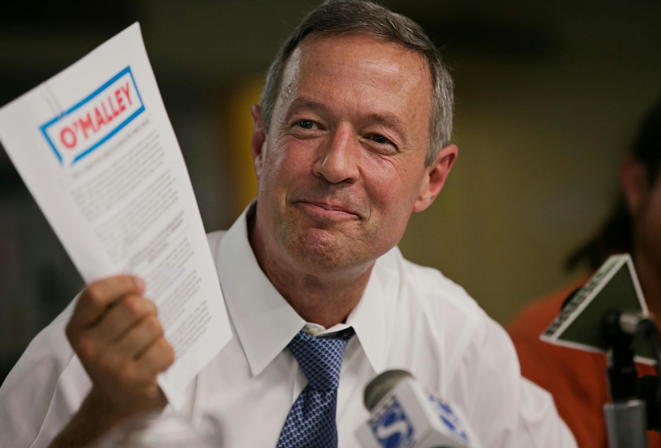 Democratic presidential candidate Martin OíMalley, center, talks about his stance on immigration and holds up a packet detailing it during a campaign stop at Trinity United Methodist Church in Des Moines, Iowa on Thursday, July 16, 2015. (Brian Powers/The Des Moines Register via AP) NO SALES, MAGS OUT, TV OUT, MANDATORY CREDIT