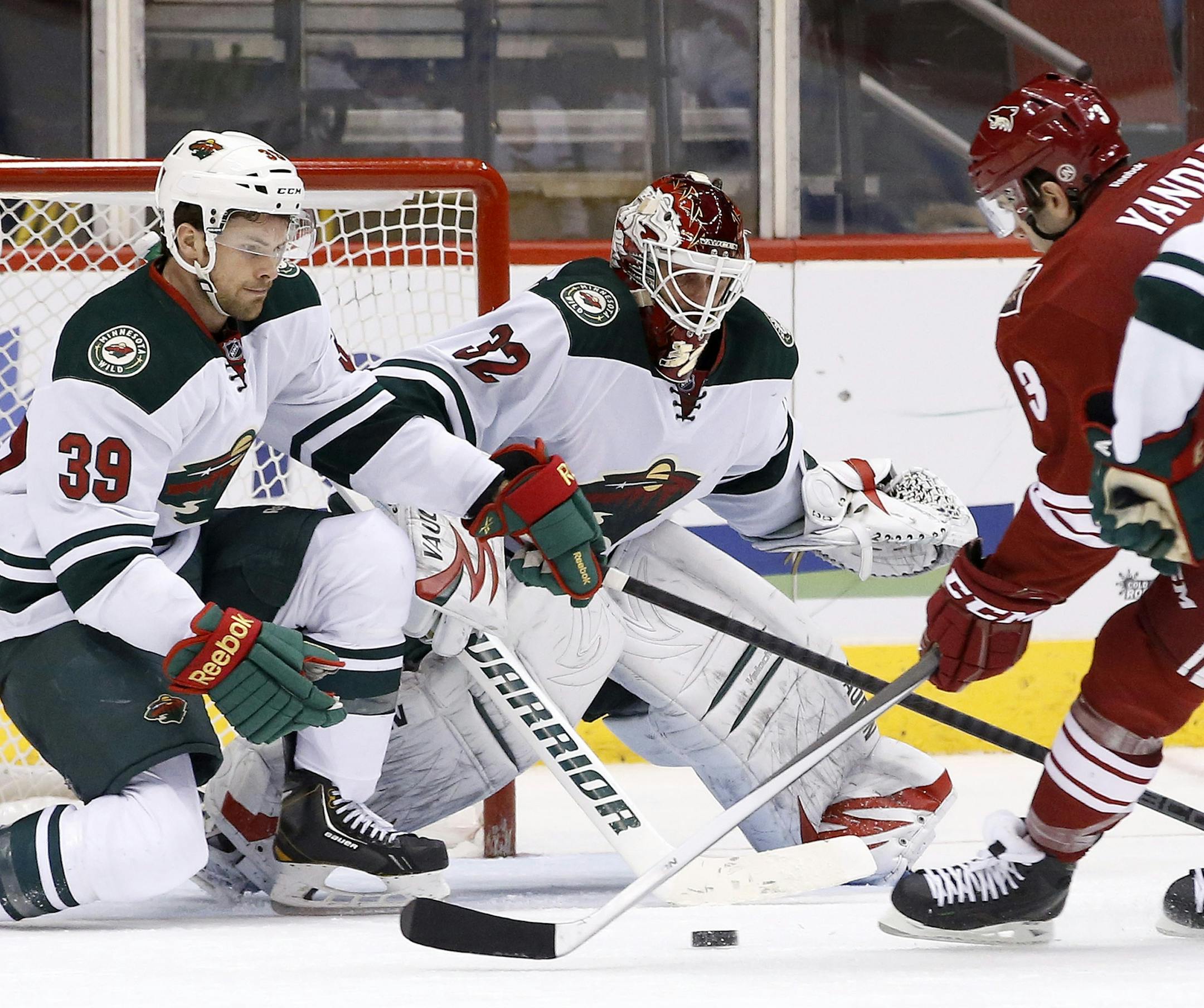 Minnesota Wild's Niklas Backstrom (32), of Finland, gets some help blocking the net from teammate Nate Prosser (39) as Phoenix Coyotes' Keith Yandle (3) gets a shot off during the third period in an NHL hockey game Thursday, Jan. 9, 2014, in Glendale, Ariz. The Wild defeated the Coyotes 4-1. (AP Photo/Ross D. Franklin)