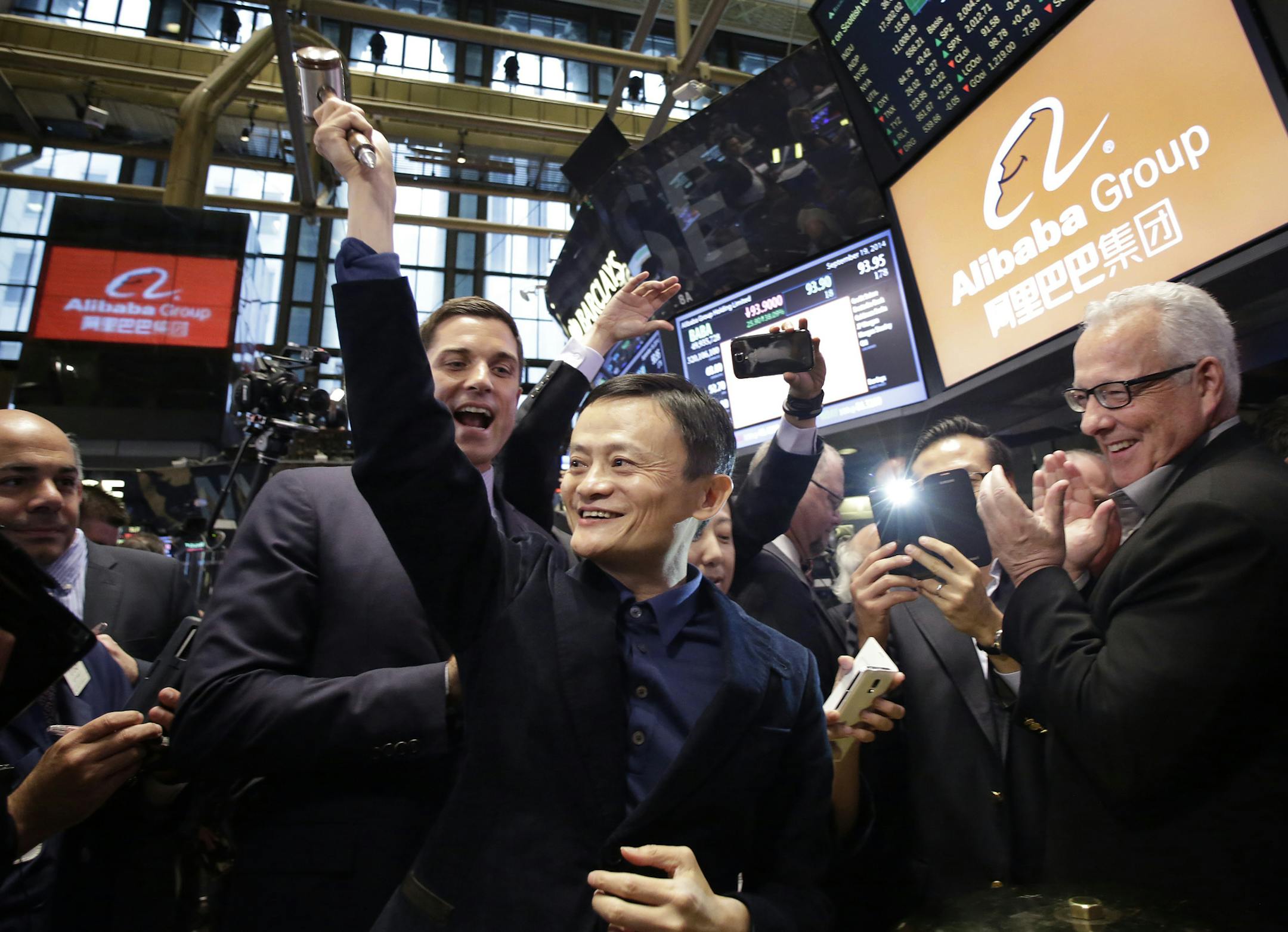 Jack Ma, center, founder of Alibaba, raises a ceremonial mallet before striking a bell during the company's IPO at the New York Stock Exchange, Friday, Sept. 19, 2014 in New York. The stock is to start trading Friday under the ticker "BABA." (AP Photo/Mark Lennihan)