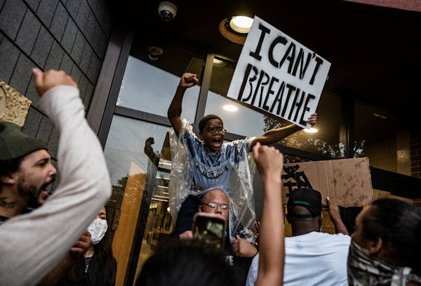 People held signs at the Minneapolis police Third Precinct station after people gathered at 38th Street and Chicago Avenue during a rally for George F