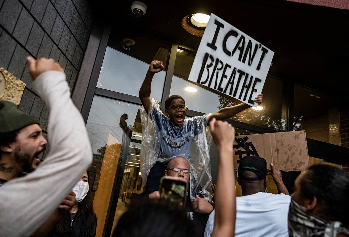 People held signs at the Minneapolis police Third Precinct station after people gathered at 38th Street and Chicago Avenue during a rally for George Floyd in 2020.