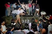 FILE - In this early June 4, 1989, file photo, civilians hold rocks as they stand on a government armored vehicle near Changan Boulevard in Beijing. O