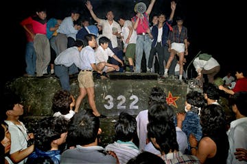 FILE - In this early June 4, 1989, file photo, civilians hold rocks as they stand on a government armored vehicle near Changan Boulevard in Beijing. O