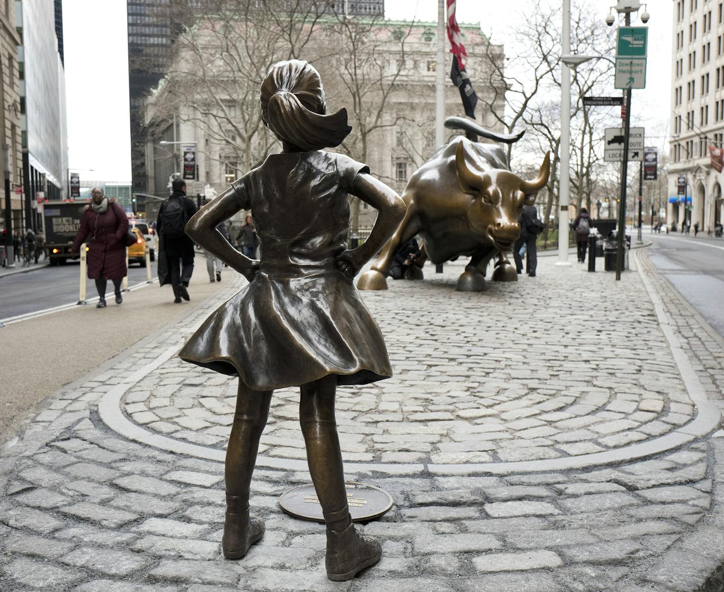 In this March 8, 2017 file photo, the Fearless Girl statue faces Wall Street's Charging Bull statue in New York. The statue that has become a global symbol of female can-do business spirit, has been removed from her spot facing the "Charging Bull" to await a new home by the New York Stock Exchange. (AP Photo/Mark Lennihan, File)