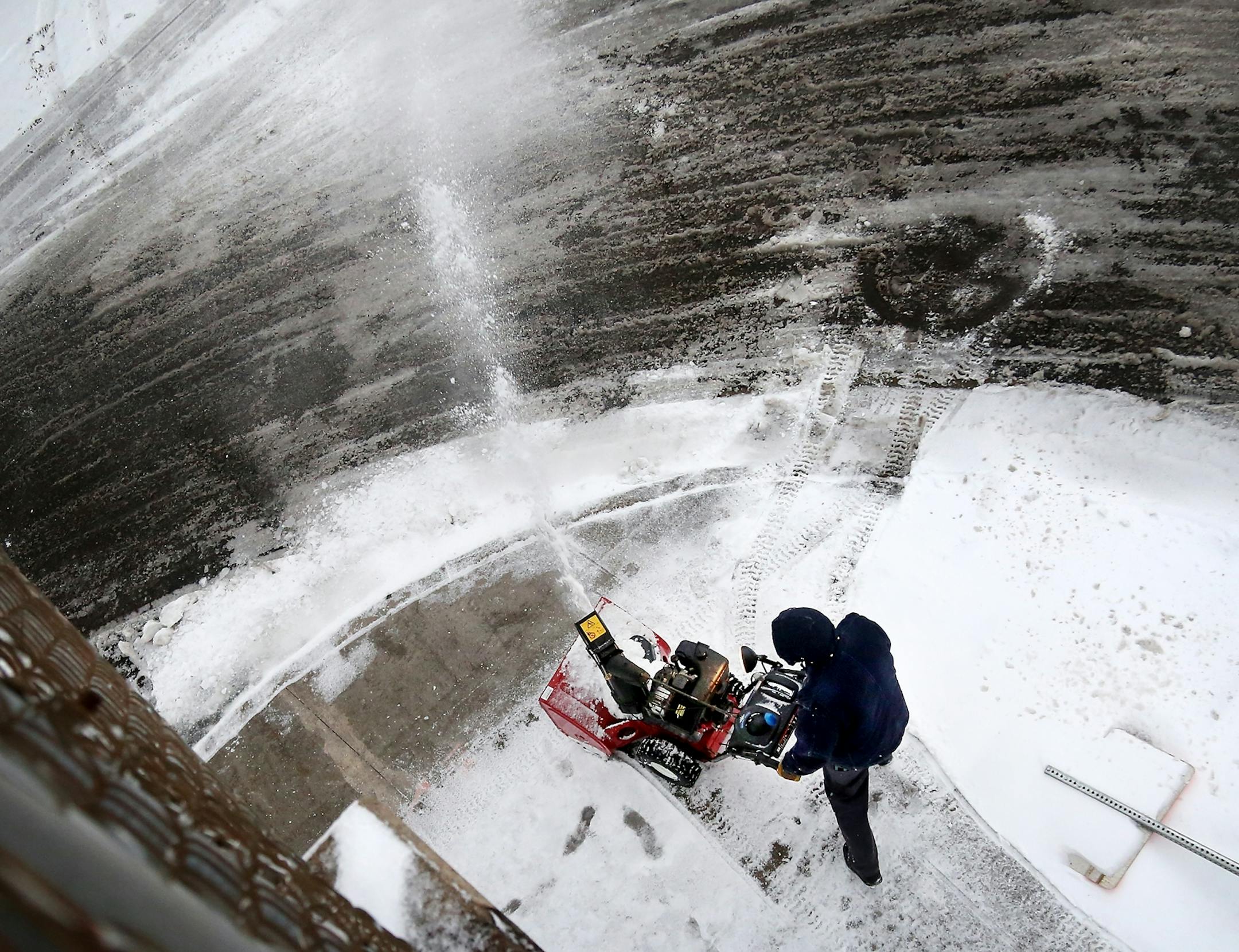 Seen from the 24th Street foot bridge, a man blows snow Saturday, April 14, 2018, in Minneapolis, MN.