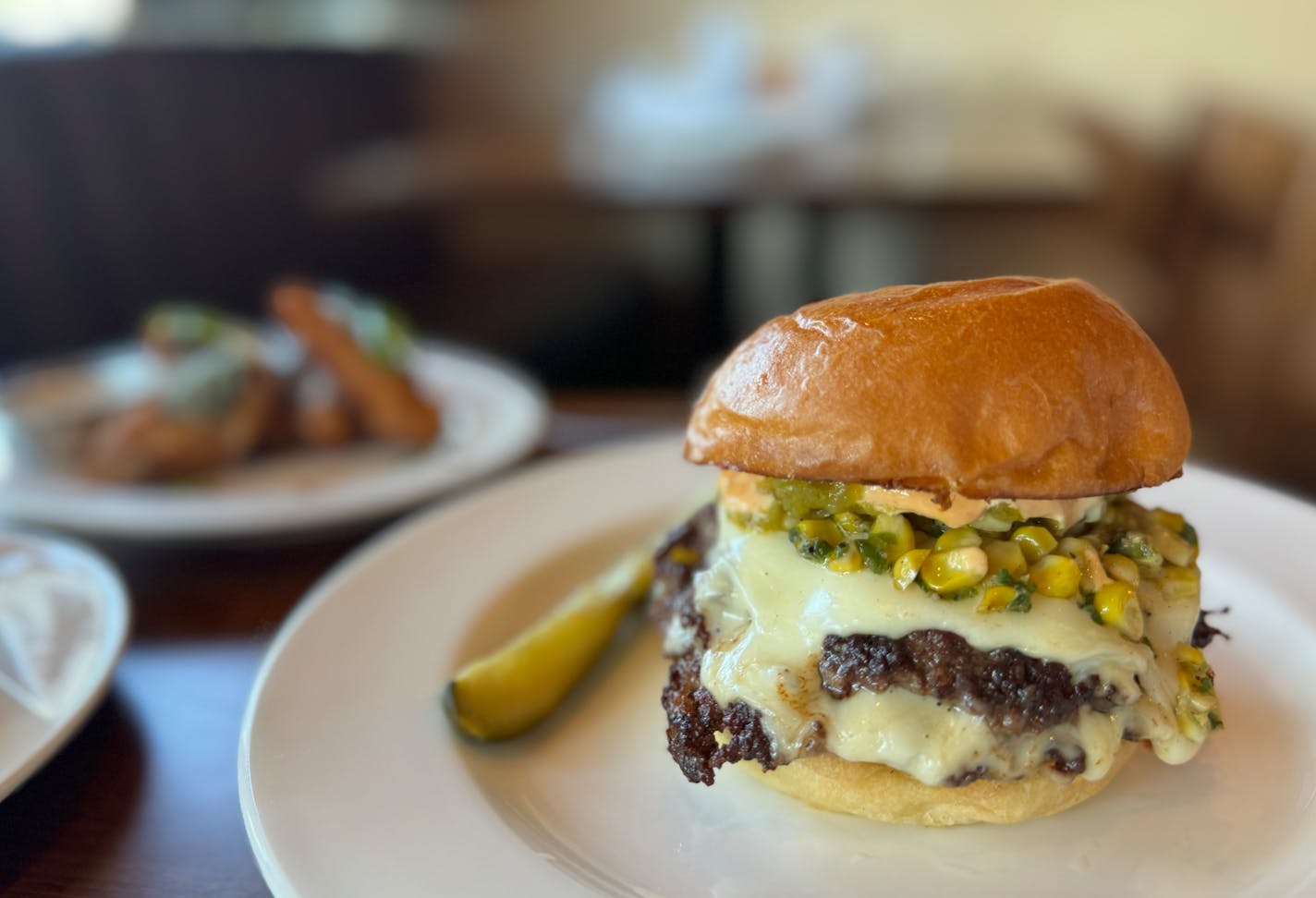 The elote smash burger burger at Dexter's sports bar in Minneapolis is piled high with two patties, charred corn, white American cheese, chipotle mayo, jalapeno and cilantro.