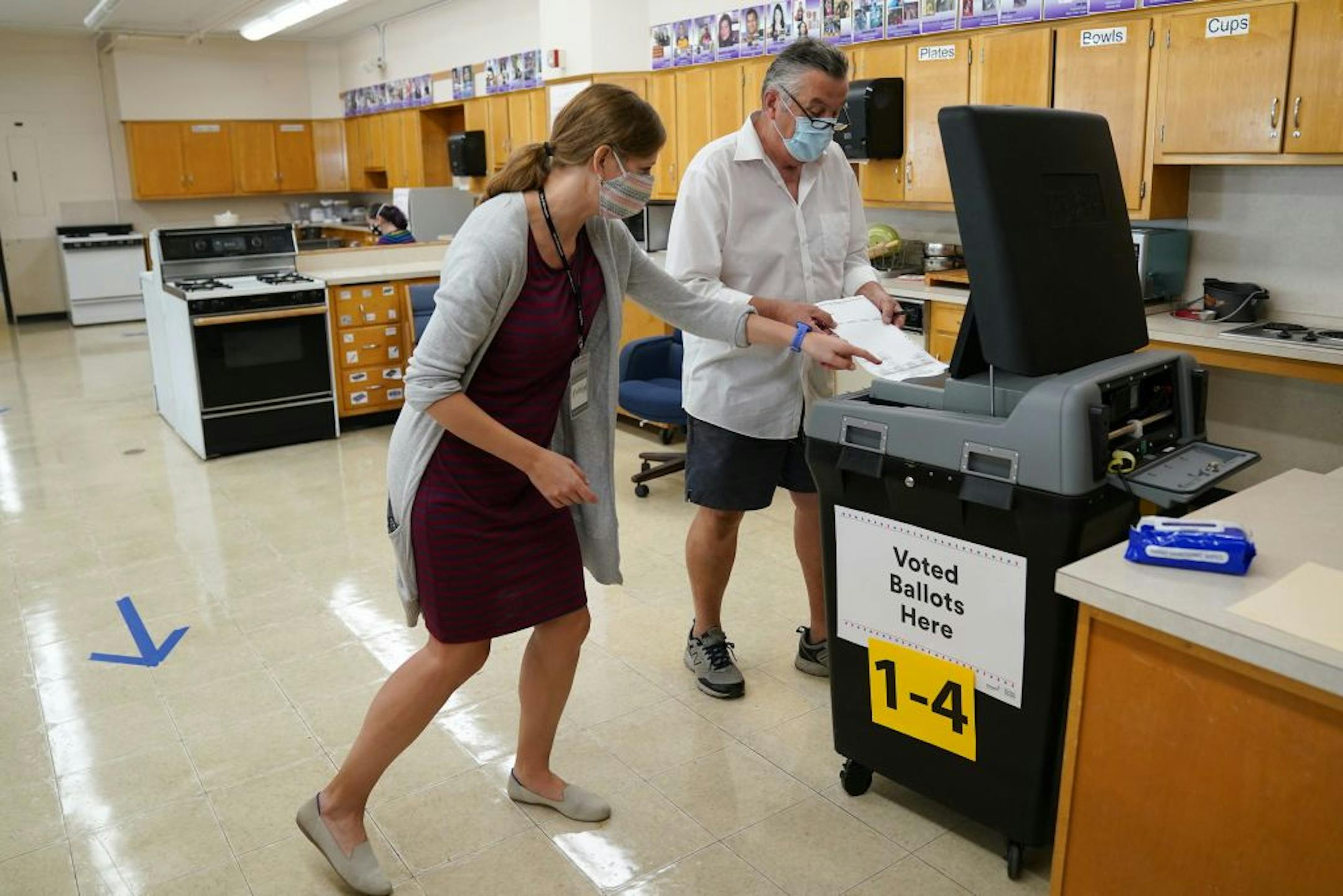 Election judge Katelyn Engel helped voter Tom Dunnwald submit his ballot Tuesday morning at Northeast Middle School in Minneapolis.
