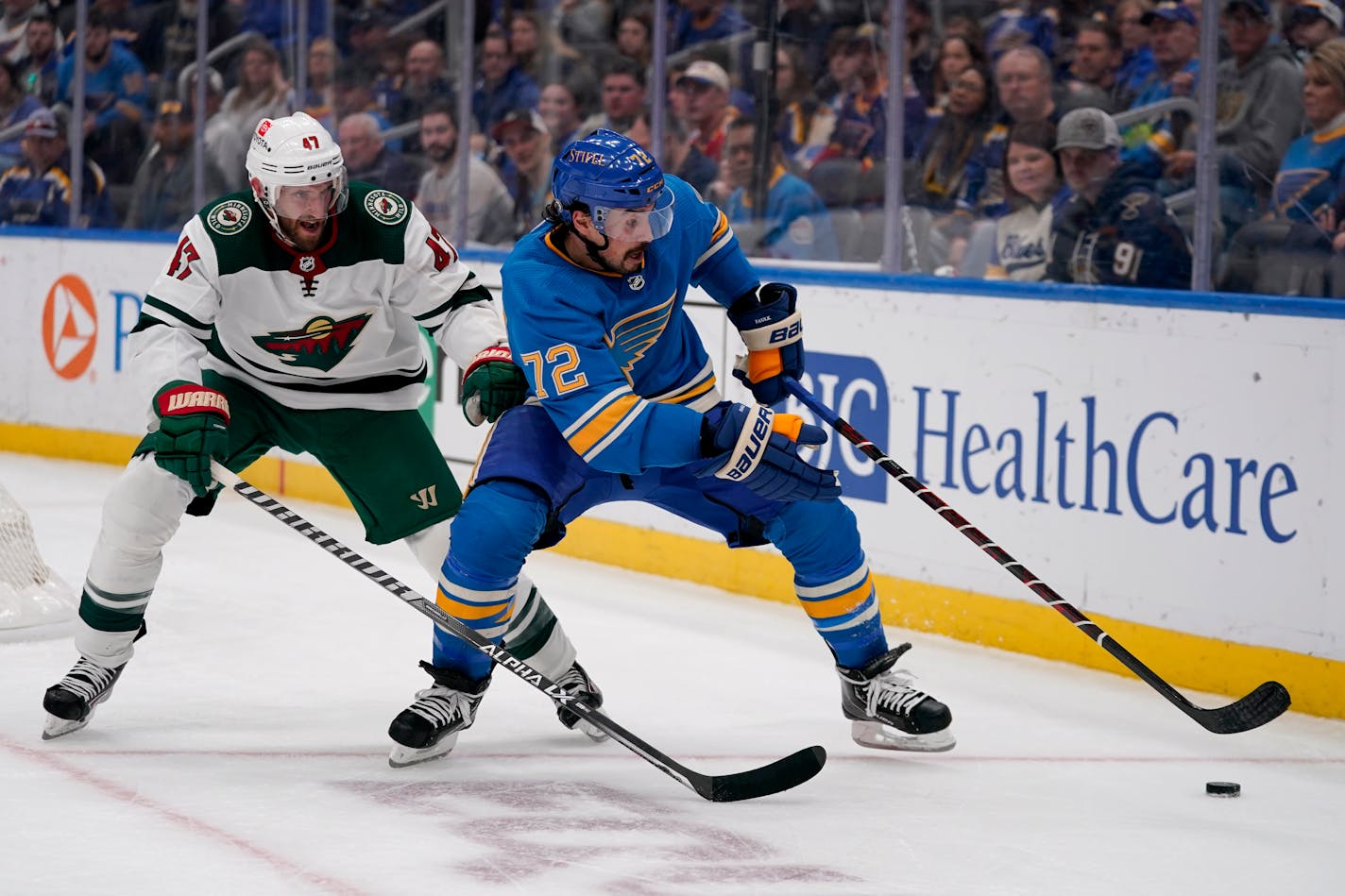 St. Louis Blues' Justin Faulk (72) and Minnesota Wild's Alex Goligoski (47) chase after a loose puck along the boards during the third period of an NHL hockey game Saturday, April 16, 2022, in St. Louis. (AP Photo/Jeff Roberson)