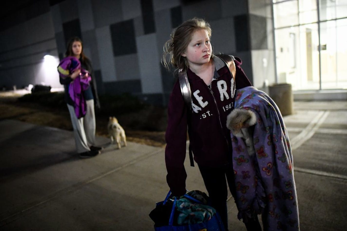 Natalia Johnson, 12, right, and her sister Iley, 15, stood outside Amsoil Arena in Duluth with their 6-year old pug, Tucker, and some of their belongings following the evacuation of Superior, Wis., on Thursday.