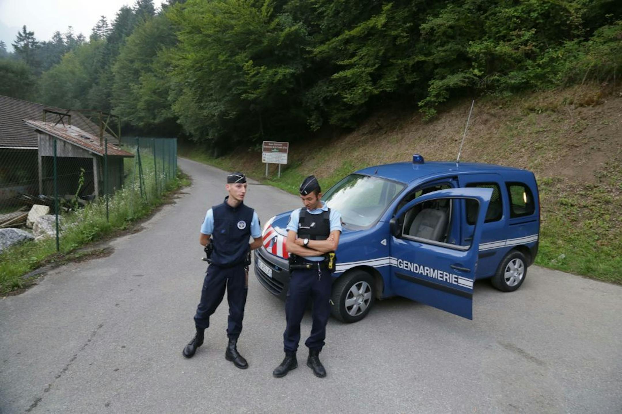 Gendarmes block access to a killing site near Chevaline, French Alps, Wednesday Sept. 5, 2012. French authorities say at least four people have been shot to death in a forest in the Alps. An official with the regional administration for the Haute-Savoie region says three of the bodies were found in a BMW registered in Britain.
