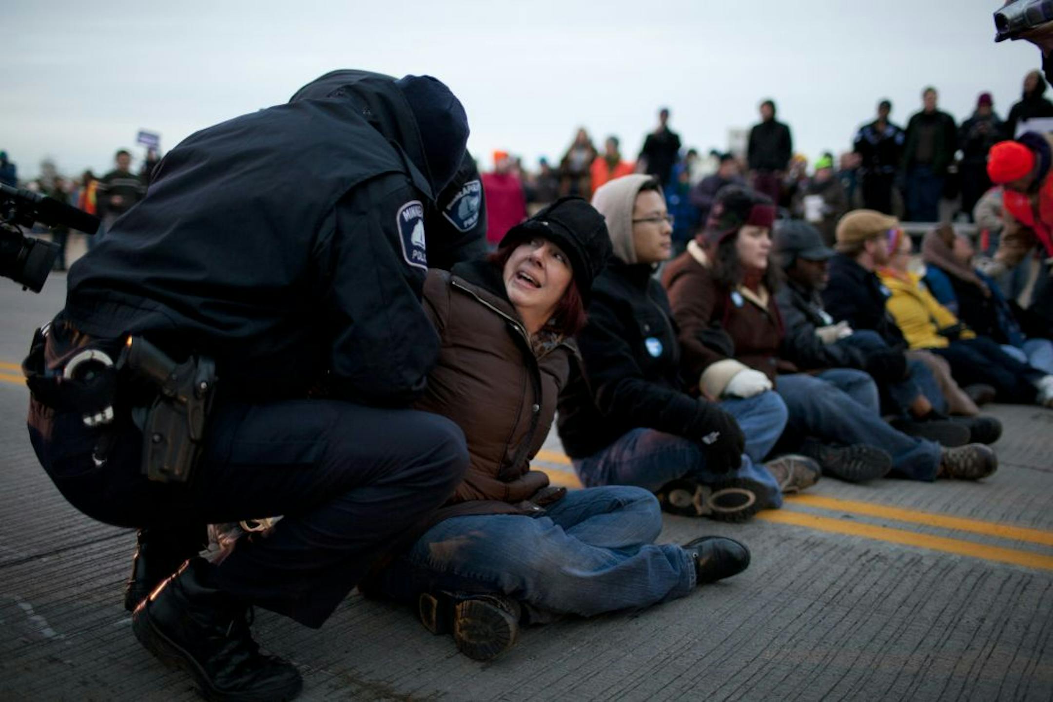 Protesters, including Donna Cassult, left, of Minneapolis, linked arms and sat on the 10th Ave. Bridge roadway waiting to be arrested.
