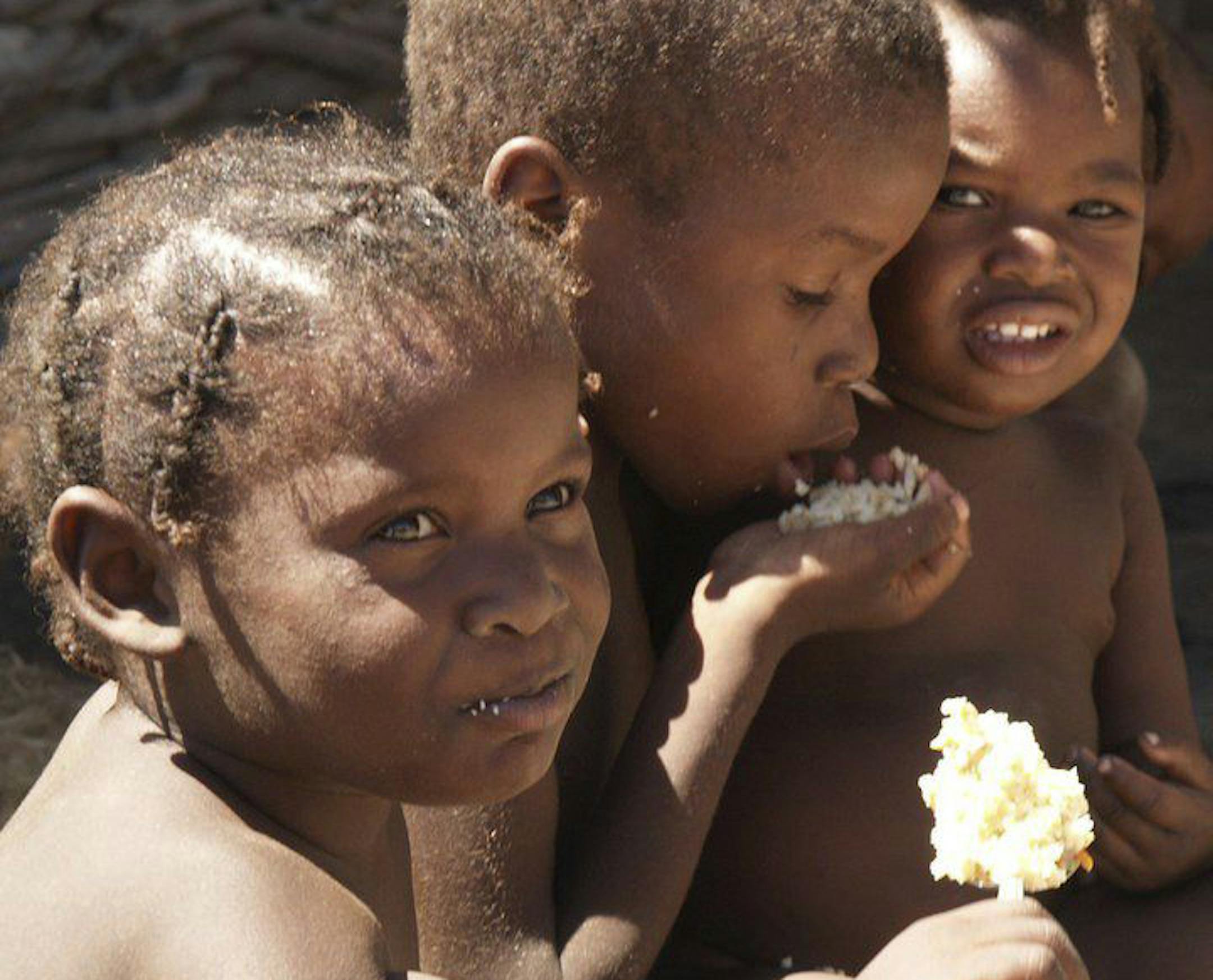 Haiti children eating food provided by Feed My Starving Children. Their reddish hair is a sign of malnutrition.