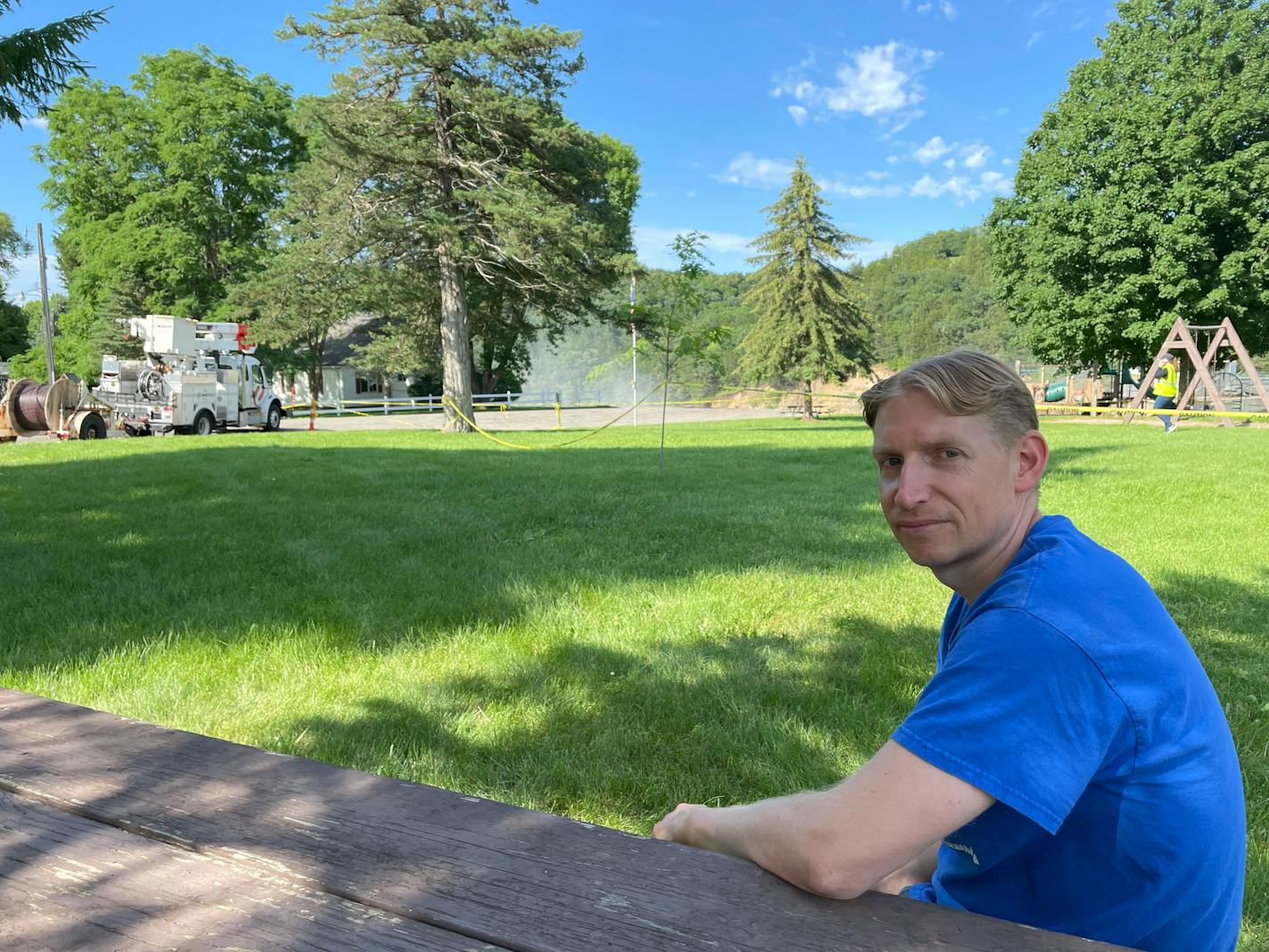 A man sits with his childhood home in the background. The home would later collapse due to erosion caused by flooding of nearby Rapidan Dam.