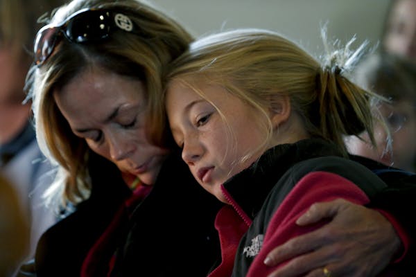 Molly Delaney, left, holds her 11-year-old daughter, Milly Delaney, during a service in honor of the victims who died a day earlier when a gunman open