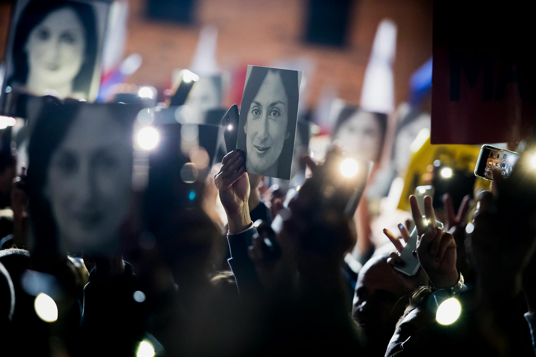 People hold pictures of slain Maltese journalist Daphne Caruana Galizia as they protest outside the office of the Maltese Prime Minister Joseph Muscat in Valletta, Malta, on Nov. 29, 2019. Galizia was killed by a car bomb in 2017.
