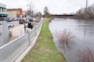 A flood wall stands on the bank of the Crow River as waters rise near Bridge Ave E. Wednesday, April 19, 2023, in Delano, Minn.