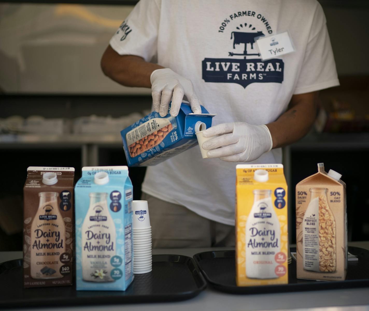 Tyler Hatley poured a sample of vanilla flavored Dairy + Almond milk blend for a fairgoer. ] JEFF WHEELER &#x2022; jeff.wheeler@startribune.com Live Real Farms, a 100% farmer owned producer of a first-ever blended milk product that includes both lactose free dairy and plant-based beverages like almond or oat milk is launching the product with free samples and coupons from their stand at the Minnesota State Fair in Falcon Heights. Tyler Hatley was pouring samples for fairgoers Wednesday afternoon