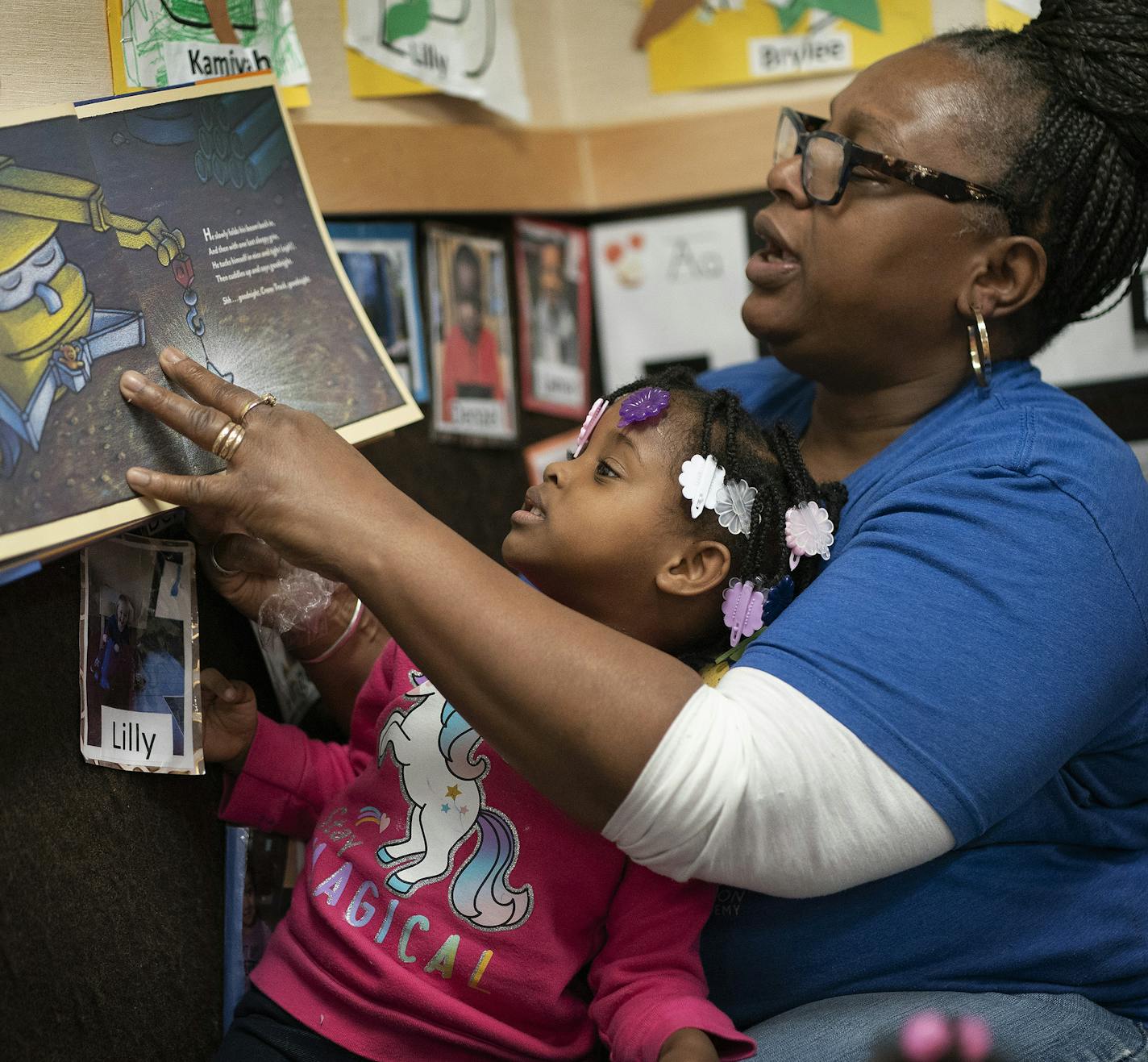 Brenda McRoy read a book about a construction site to Kamiyah Henry a preschooler at New Horizon Academy childcare center.