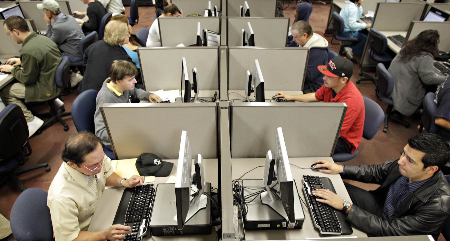 Unemployed workers fill out online resume's at the Maricopa County Workforce Connections job fair Tuesday, Nov. 23, 2010 in Phoenix. The number of people applying for unemployment benefits fell sharply last week to the lowest level since July 2008, a hopeful sign that improvement in the job market is accelerating. (AP Photo/Matt York)