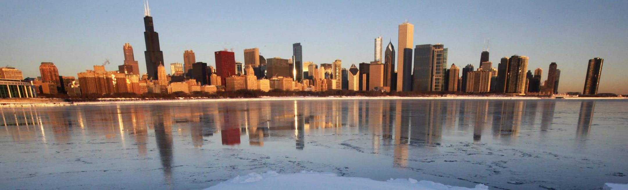 The Chicago skyline is reflected on a thin layer of ice as a chunk of snow-covered ice floats in Monroe Harbor one day after a blizzard dumped the third largest snowfall in Chicago's history, Thursday, Feb. 3, 2011. (AP Photo/Charles Rex Arbogast) ORG XMIT: MIN2013032216531556