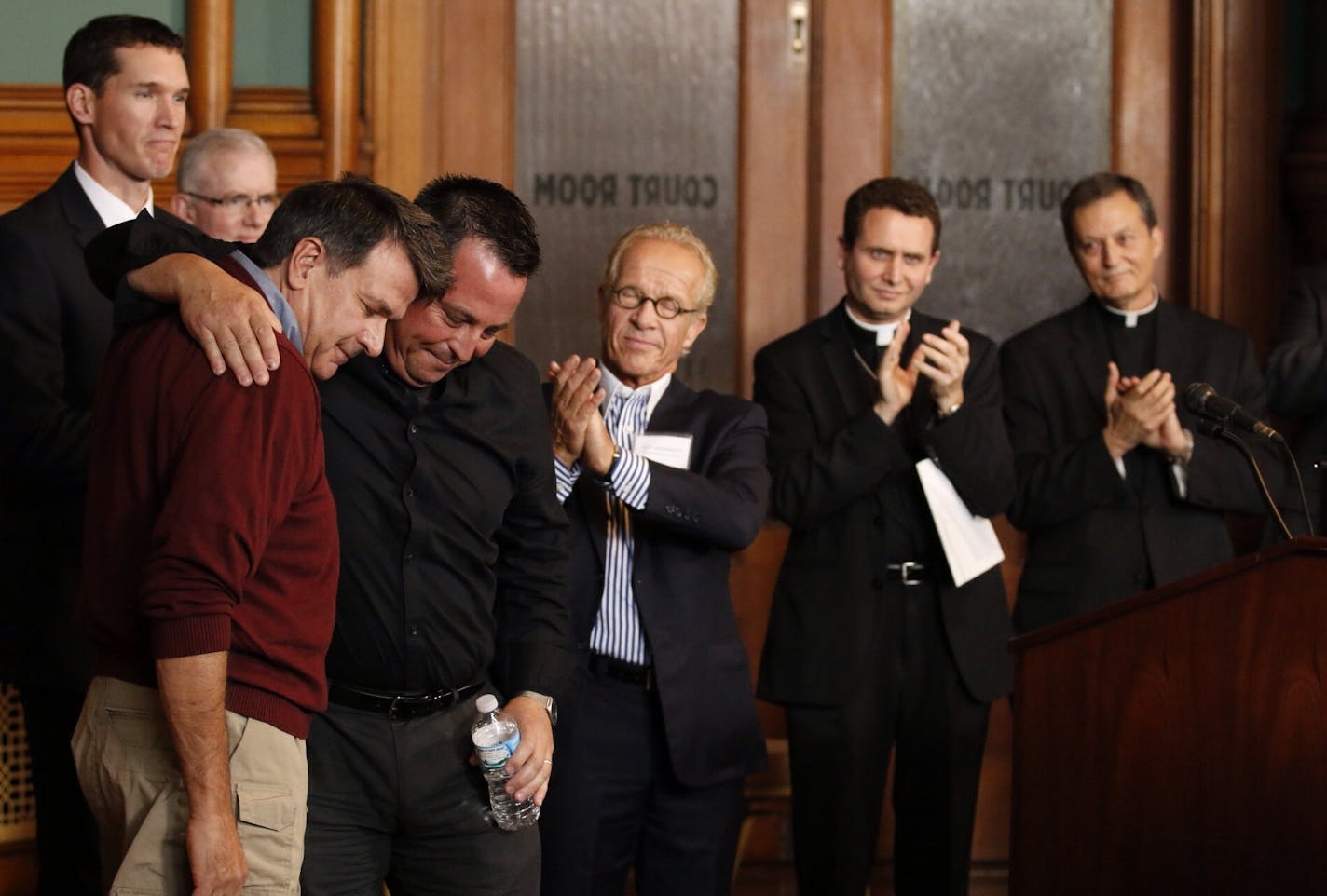 Attorney Jeff Anderson, center, attends a press conference with victims, left, and clergy, right, to discuss a settlement with the St. Paul-Minneapolis Archdiocese.