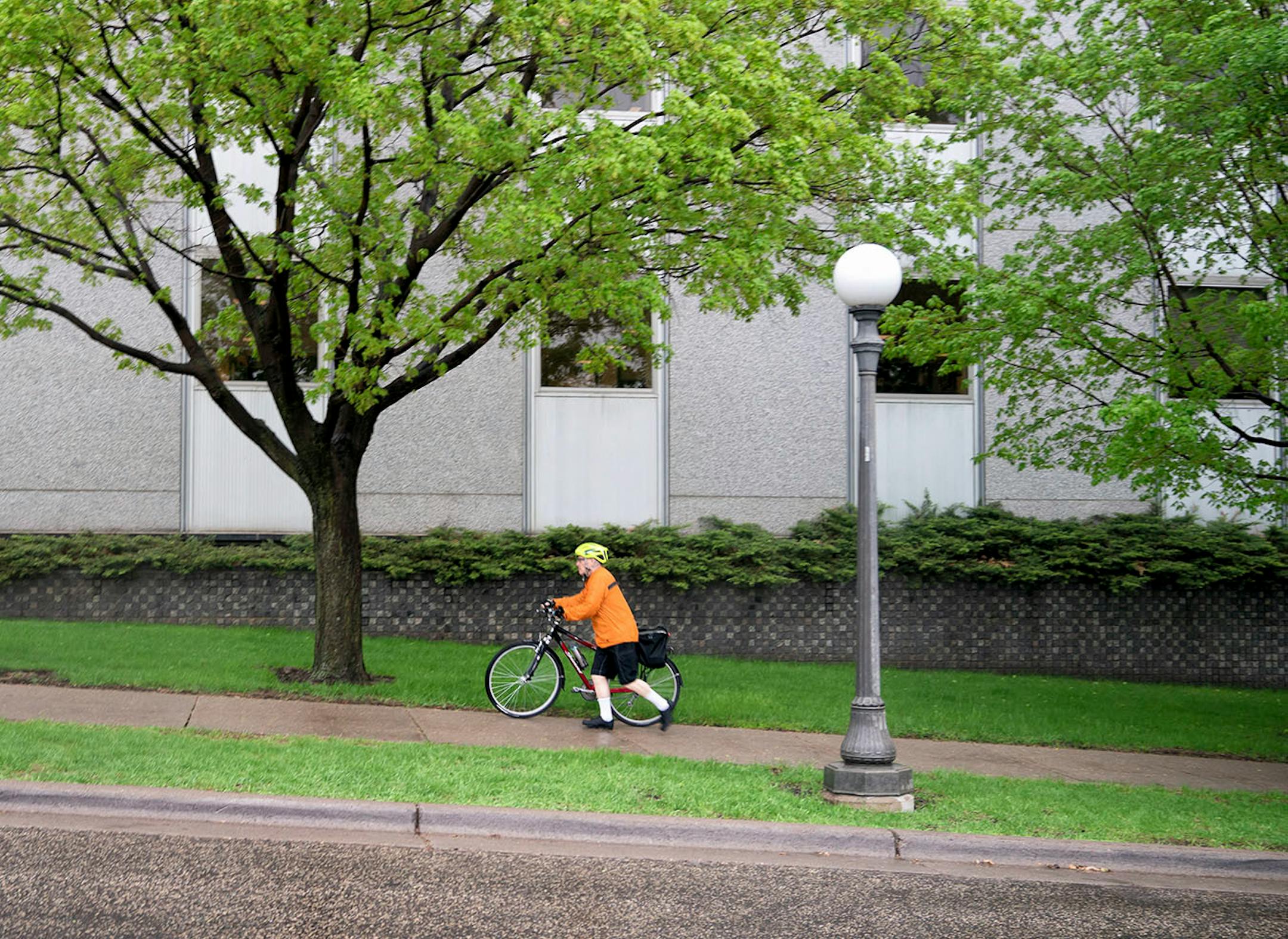 Commissioner Frans changed from his suit into a rain jacket and shorts for the 13-mile bicycle ride home to Minneapolis. Here he pushed his bike up the Cedar Ave hill.