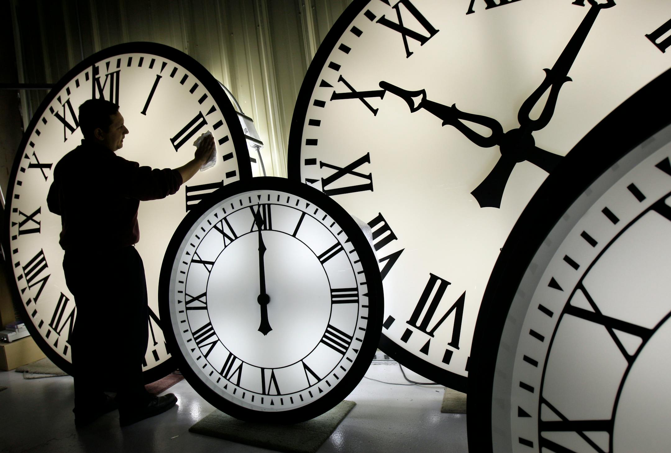In this file photo, an employee Walter Rodriguez cleans the face of an 84-inch Wegman clock at the plant in Medfield, Mass.