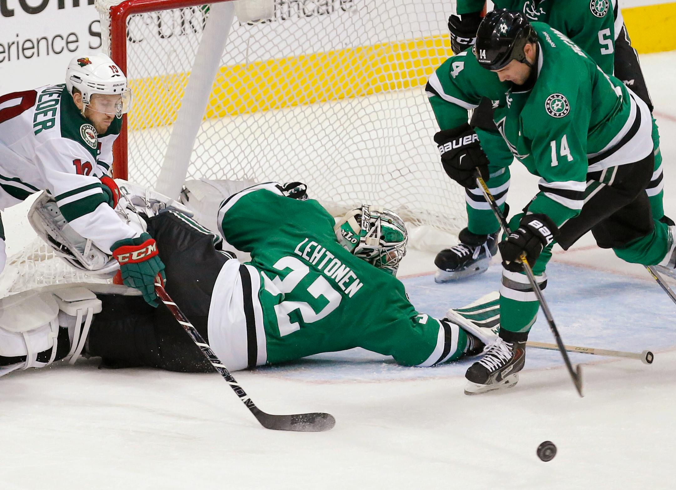 Minnesota Wild forward Jordan Schroeder (10) reaches for the puck as Dallas Stars goalie Kari Lehtonen (32) defends and forward Jamie Benn (14) looks to clear the puck during the second period of an NHL hockey game, Saturday, Nov. 14, 2015, in Dallas. (AP Photo/Brandon Wade)