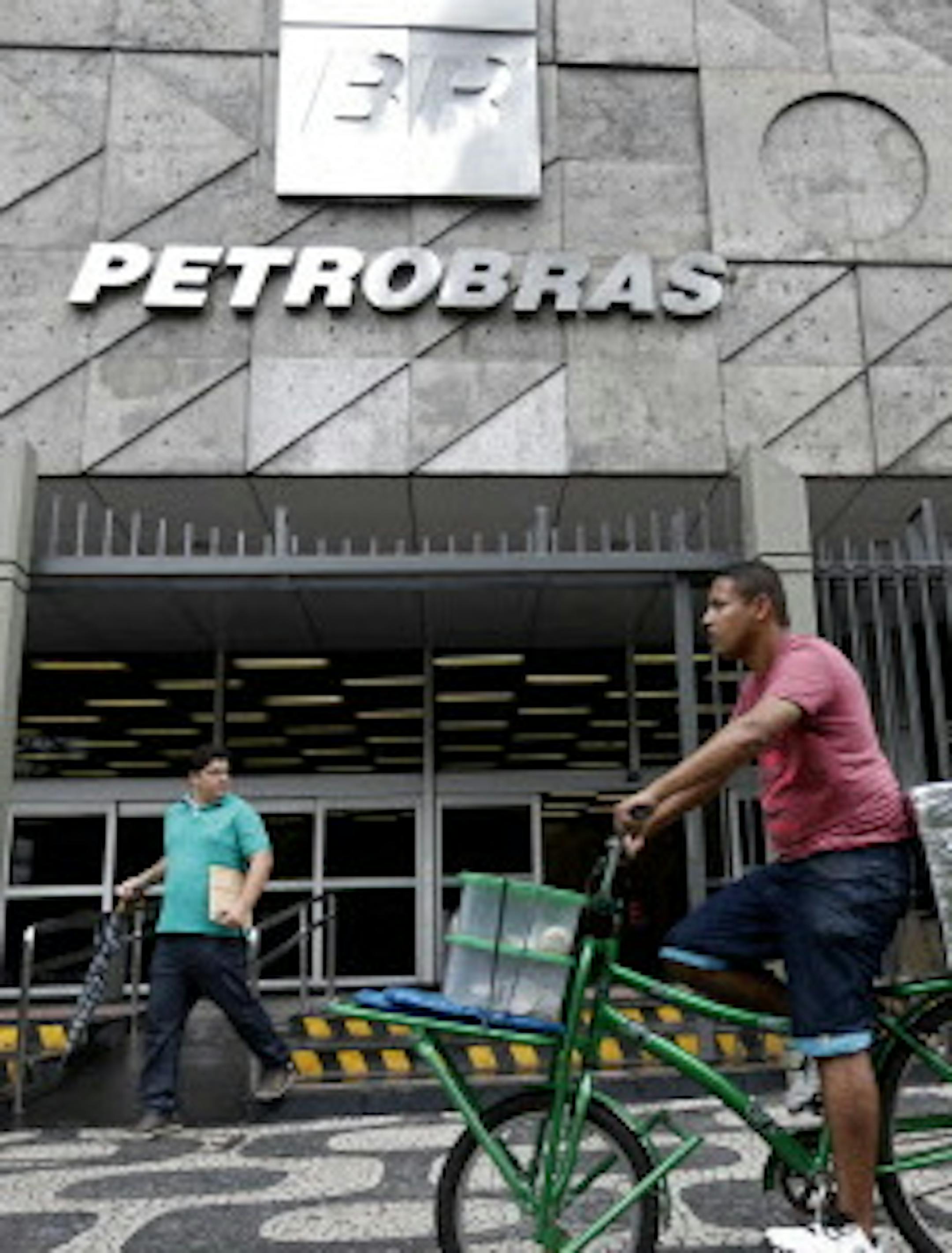 A man rides a bike in front of the Petrobras headquarters in Rio de Janeiro, Brazil, Wednesday, April 22, 2015. Brazil's state-run oil company Petrobras says it lost $2.1 billion because of inflated contracts and other costs related to a long-running kickback scheme. Federal prosecutors have called the scheme the biggest corruption case ever uncovered in Brazil. They stress that they are still investigating and says the scope of the case continues to widen. (AP Photo/Silvia zquierdo)