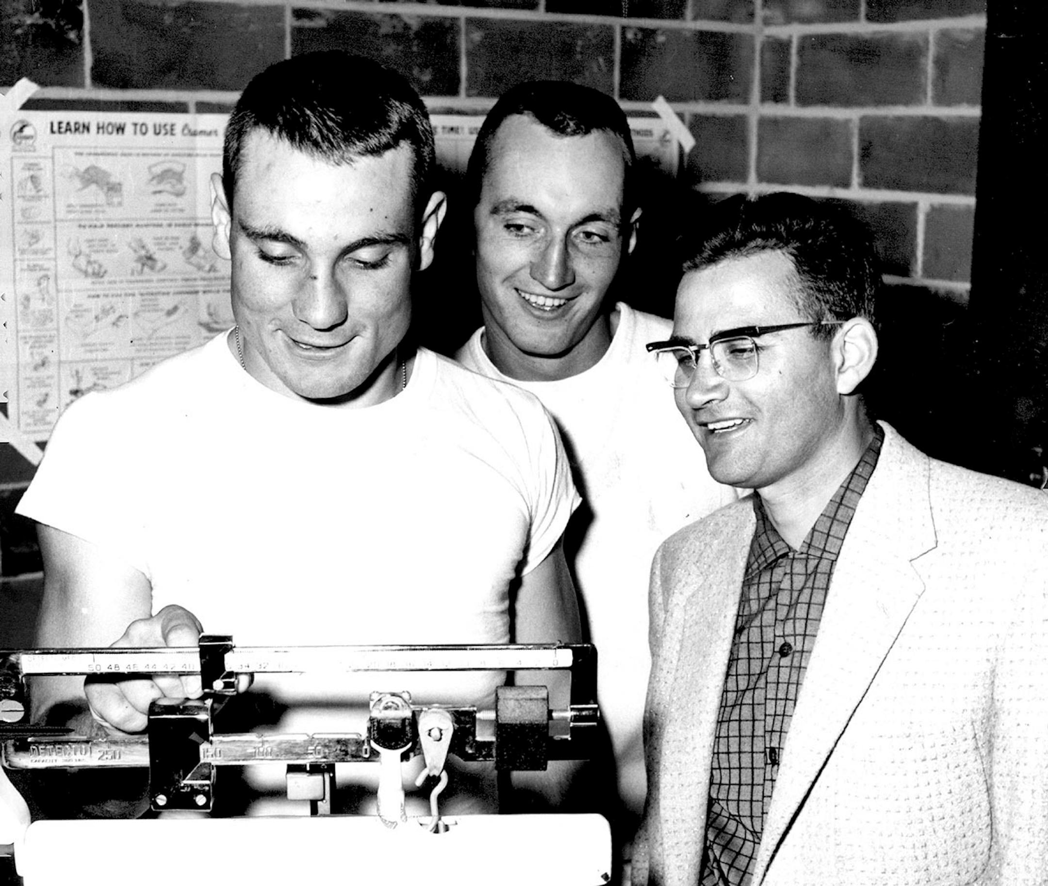 Roger Ludwig weighed in under the watchful eye of St. John's coach John Gagliardi, right, and teammate Dave Boyle in October of 1958.