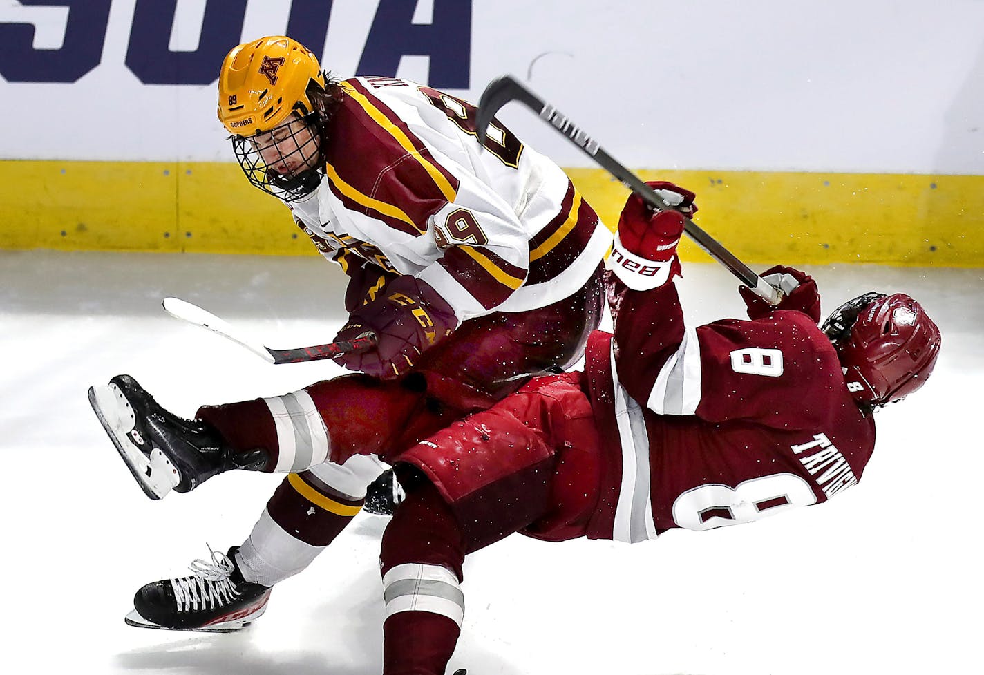 Massachusetts forward Bobby Trivigno (8) is checked by Minnesota's Matthew Knies, top, in the second period of an NCAA college hockey game in Worcester, Mass., Friday, March 25, 2022. (John Tlumacki/The Boston Globe via AP)