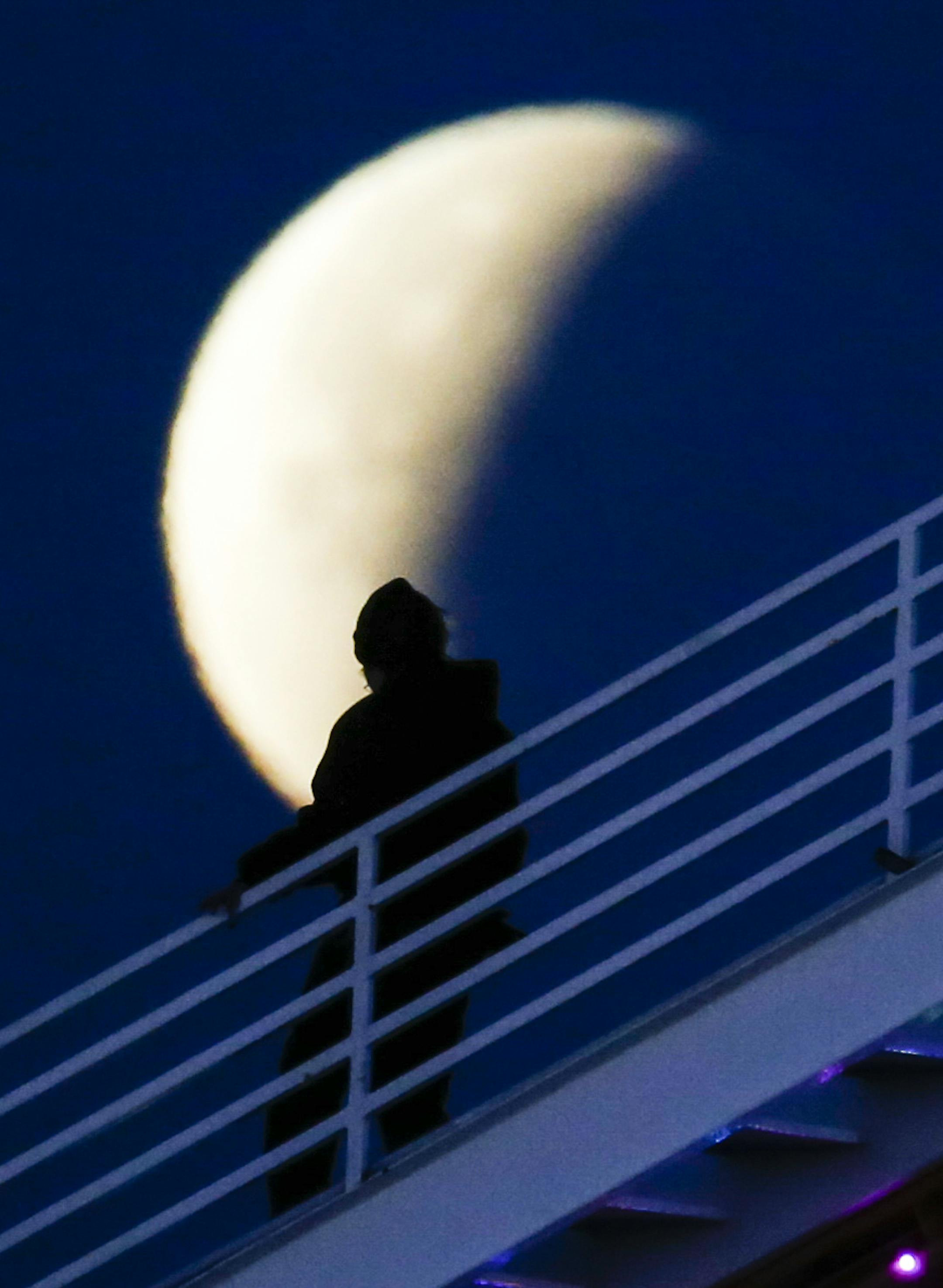 A worker of Pacific Park is silhouetted walks in front of a rare occurrence called a 'Super Blue Blood Moon' at Santa Monica Beach in Santa Monica, Calif., Wednesday, Jan. 31, 2018.
