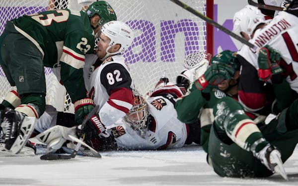 Minnesota Wild's J.T. Brown (23) and Arizona Coyotes's Jordan Oesterle (82) fight for position by the net in the second period on Tuesday, Nov. 27, 20
