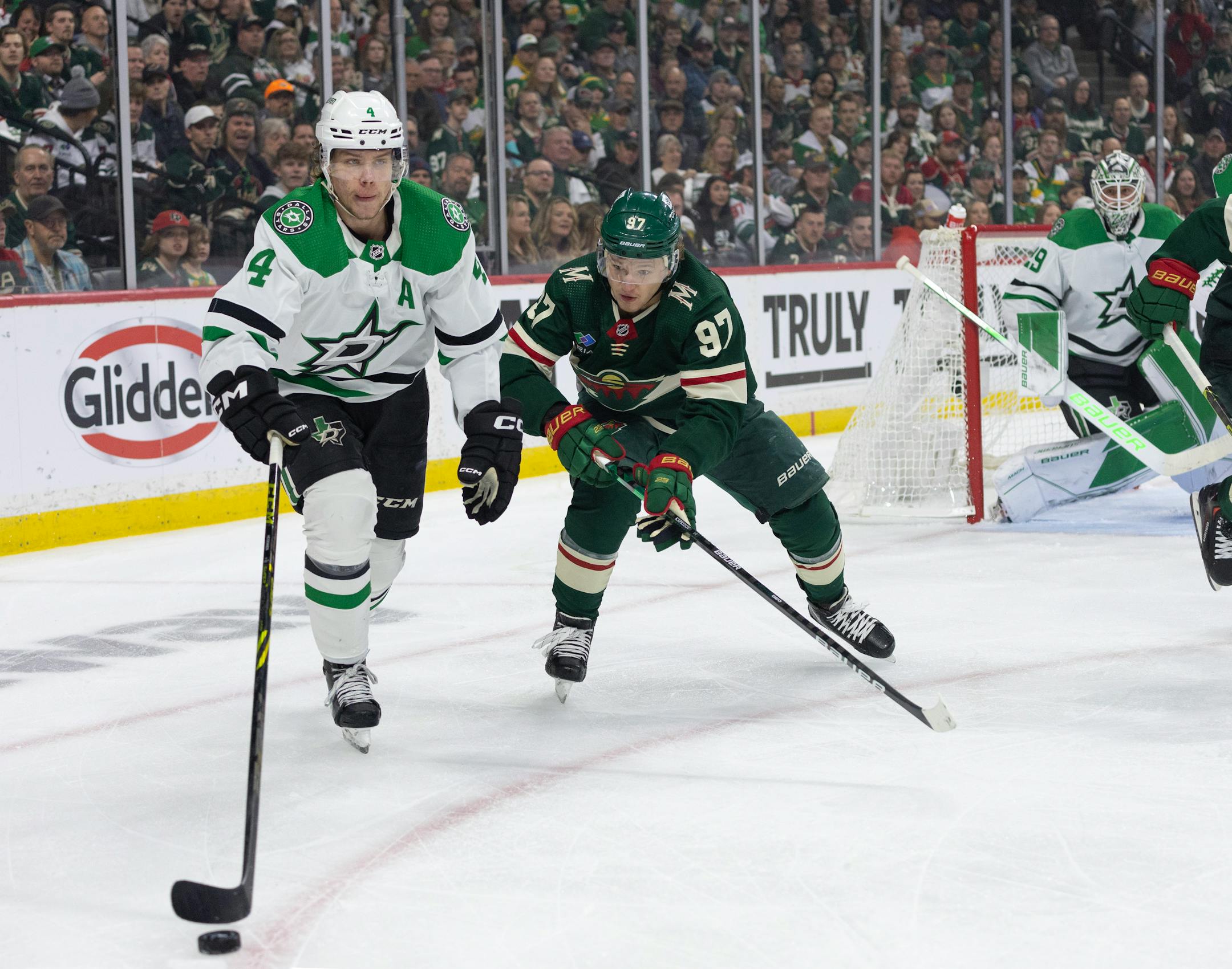 Dallas Stars defenseman Miro Heiskanen (4) tries to get the puck out of the zone while pursued by Minnesota Wild left wing Kirill Kaprizov (97) in the first period.