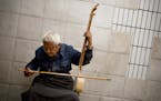 A man plays a traditional Chinese string instrument while soliciting spare change at a pedestrian underpass in Beijing, Wednesday, Sept. 30, 2015. Chi