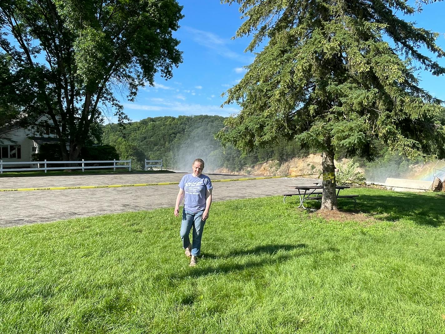 A woman walks away from a house that is about to collapse into a river due to erosion caused by the flooding of a nearby dam.