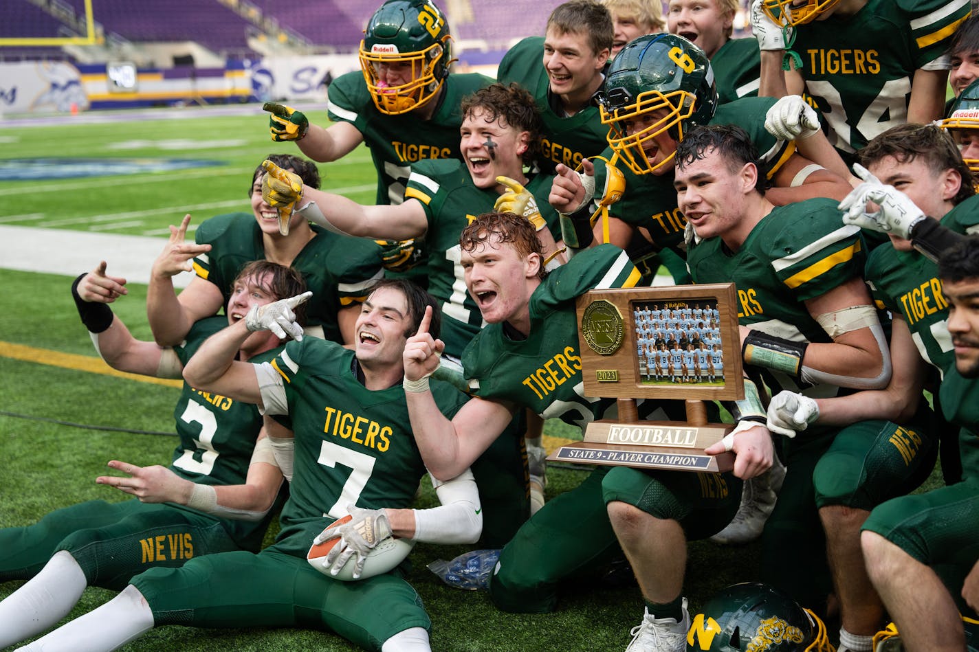 Nevis Tigers players pose for photos with their trophy after defeating Kingsland in the state 9-person football championship game at U.S. Bank Stadium in Minneapolis, Minn., on Saturday, Nov. 25, 2023. ] SHARI L. GROSS • shari.gross@startribune.com