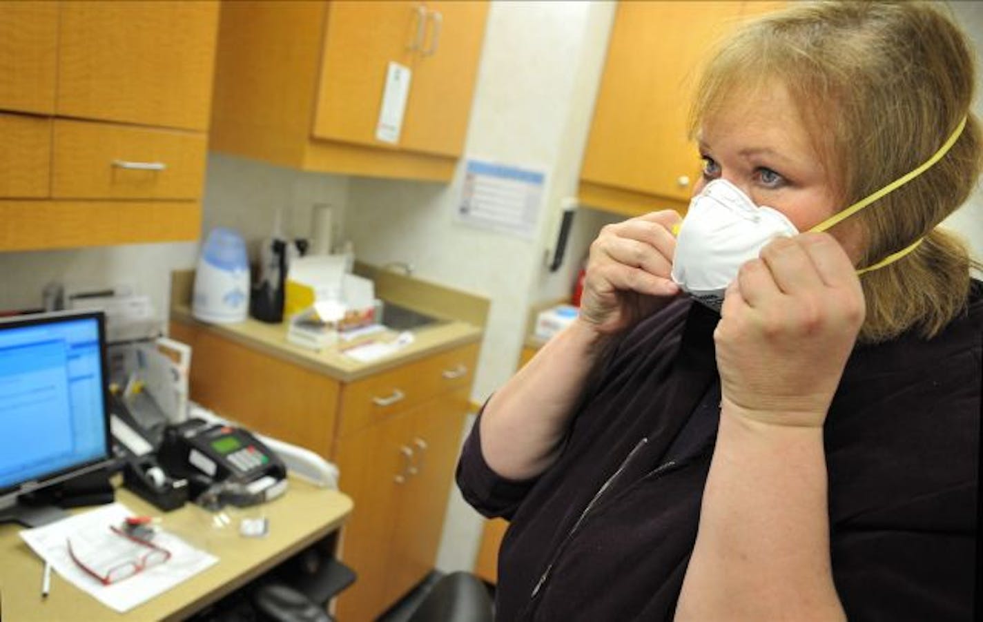 Linda Berntson, manager of operations for a Minute Clinic in Mounds View, on Thursday demonstrated the N95 mask that health care workers would wear when presented with a patient that exhibited flu-like symptoms.